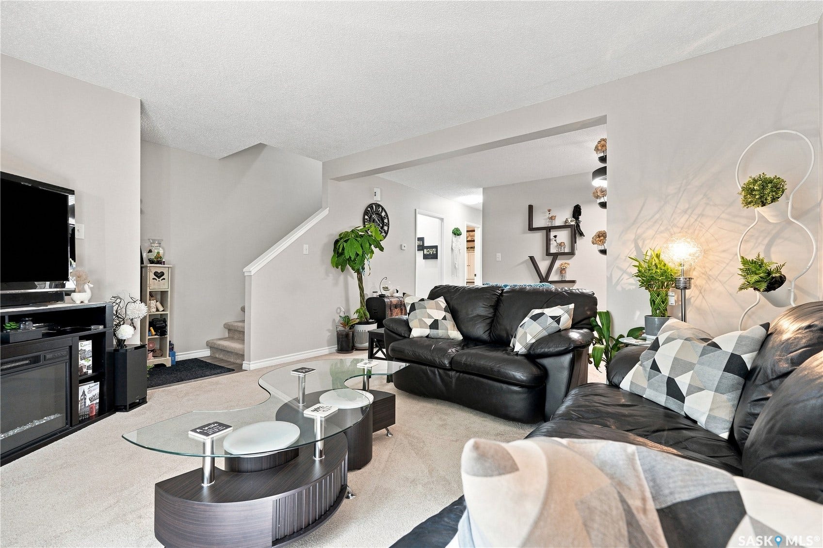 Spacious living area featuring carpet flooring, neutral wall tones, and an open entryway