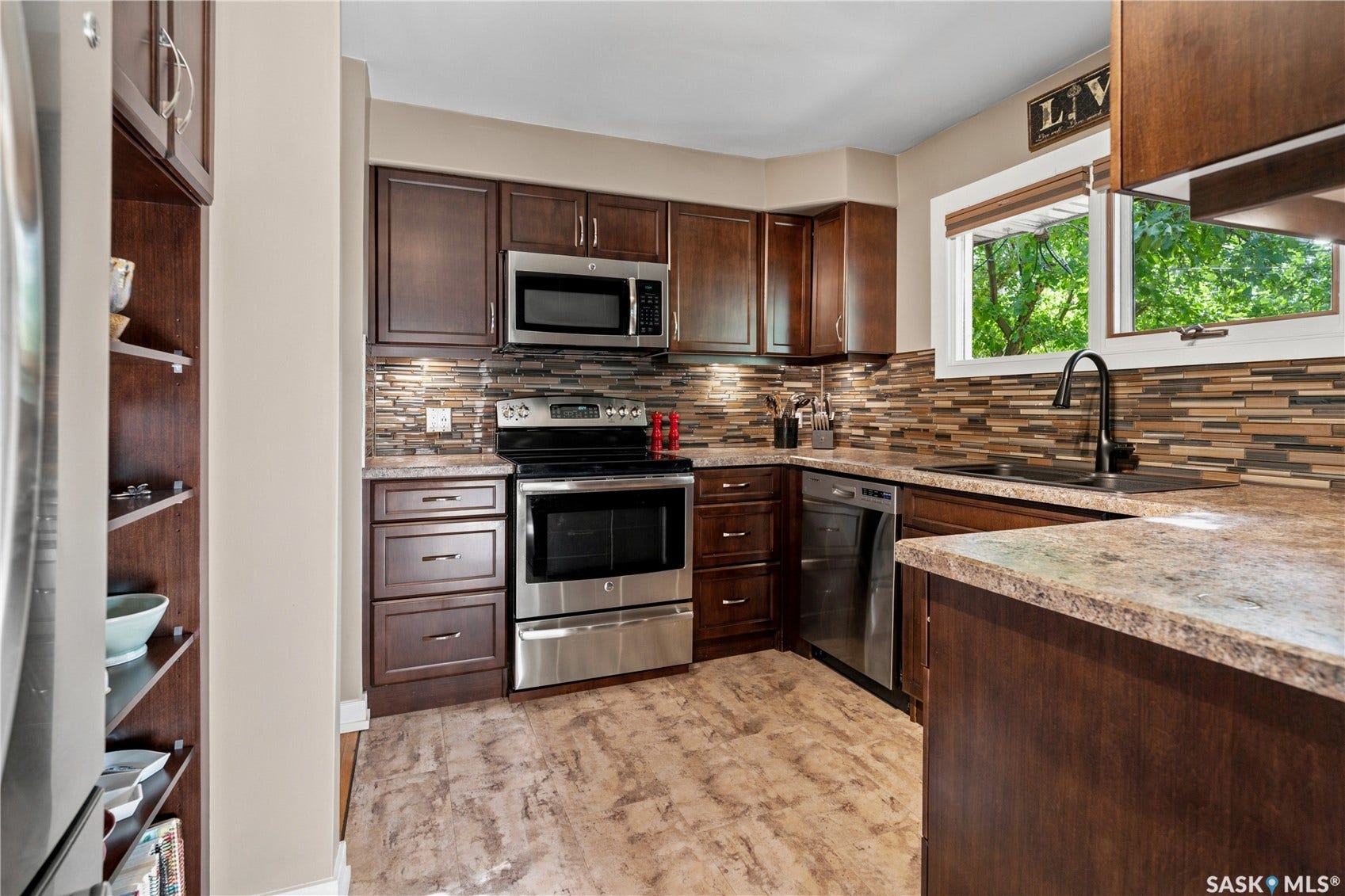 kitchen with dark cabinets and stainless steel appliances. window overlooking backyard