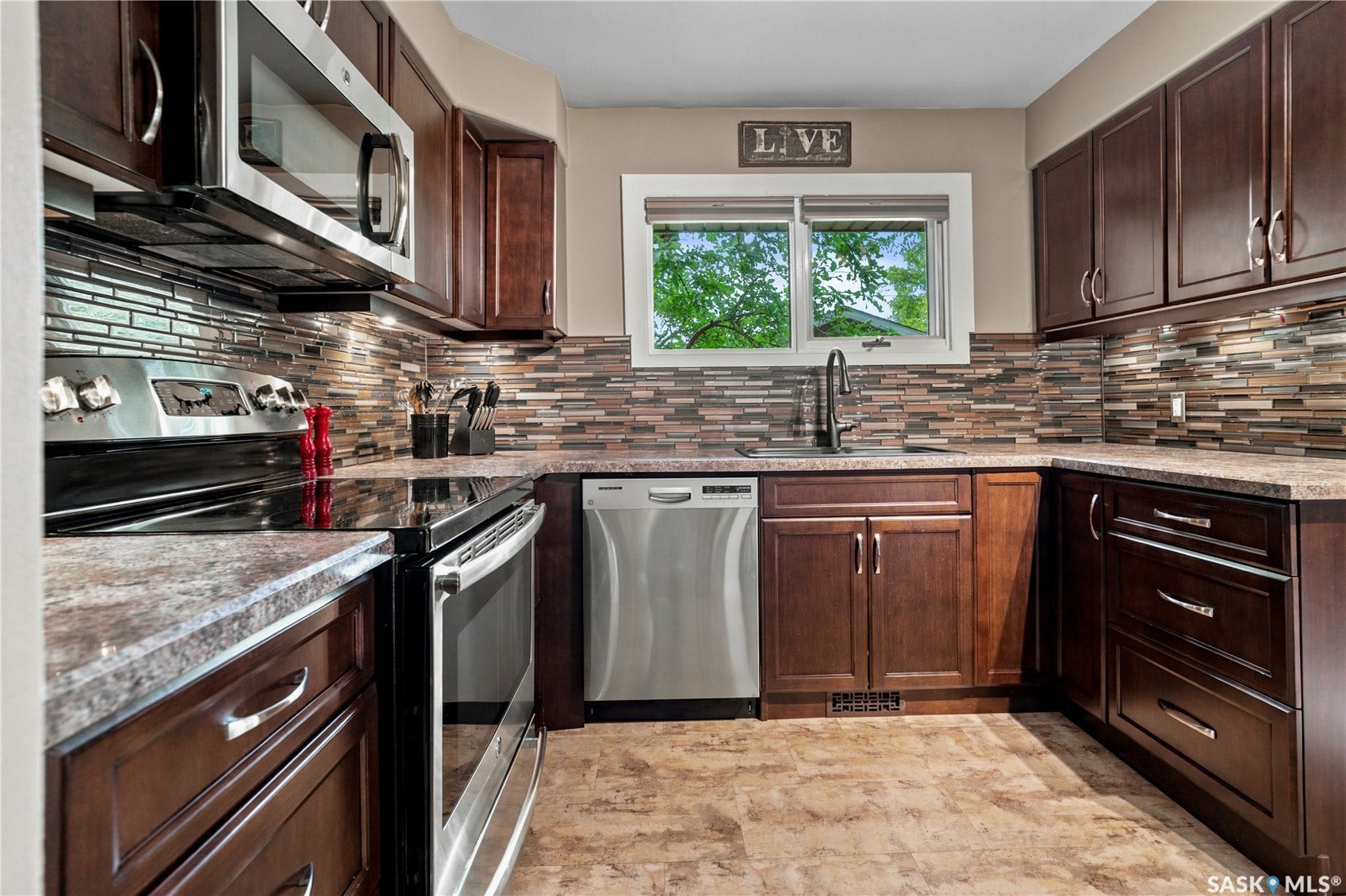 kitchen with dark cabinets and stainless steel appliances. window overlooking backyard