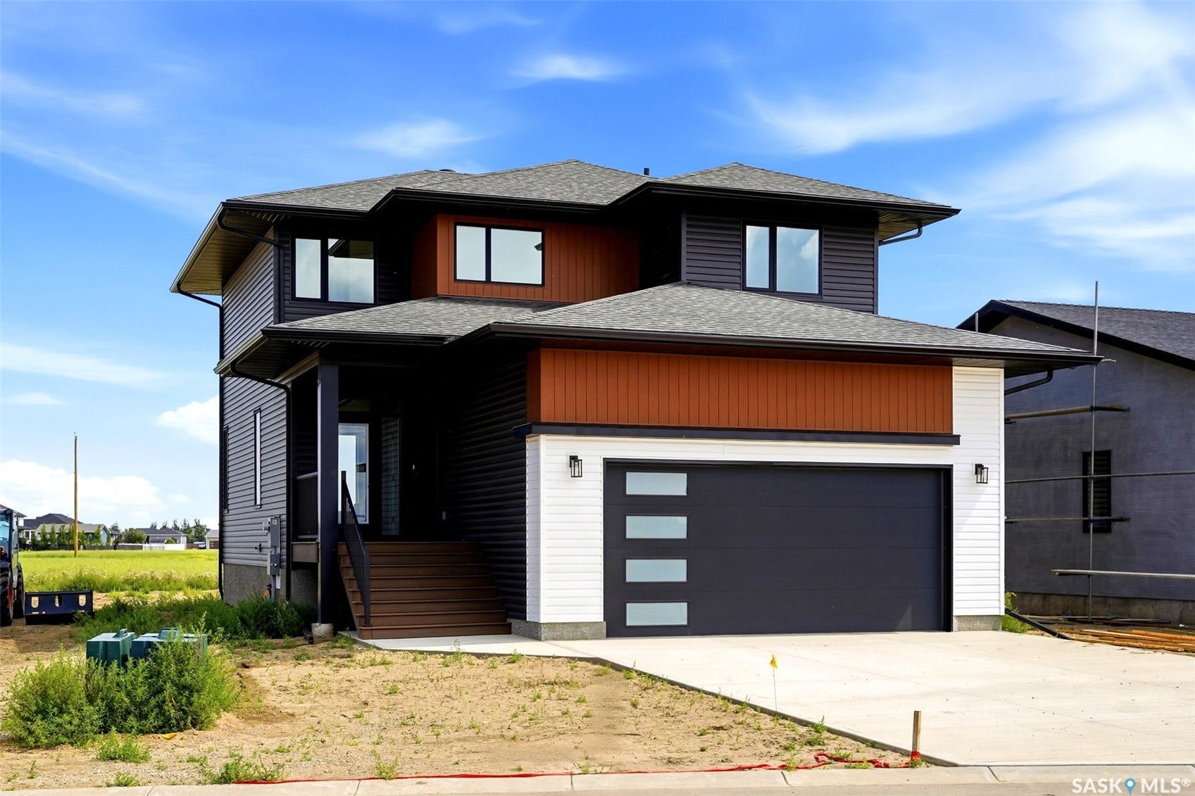 Modern exterior design featuring dark siding, contrasting wood-finish accents, a contemporary garage door with frosted panels, a covered entry, and multi-pane windows