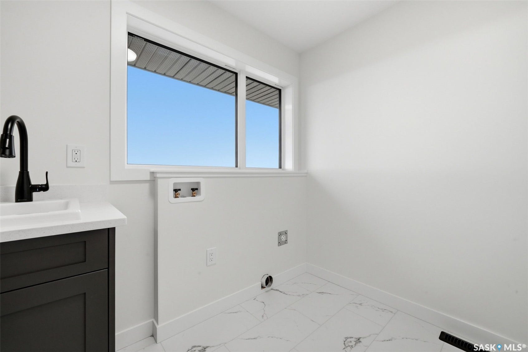White walls, white-framed window, black vanity with white countertop, black gooseneck faucet, and white marble-look floor tiling