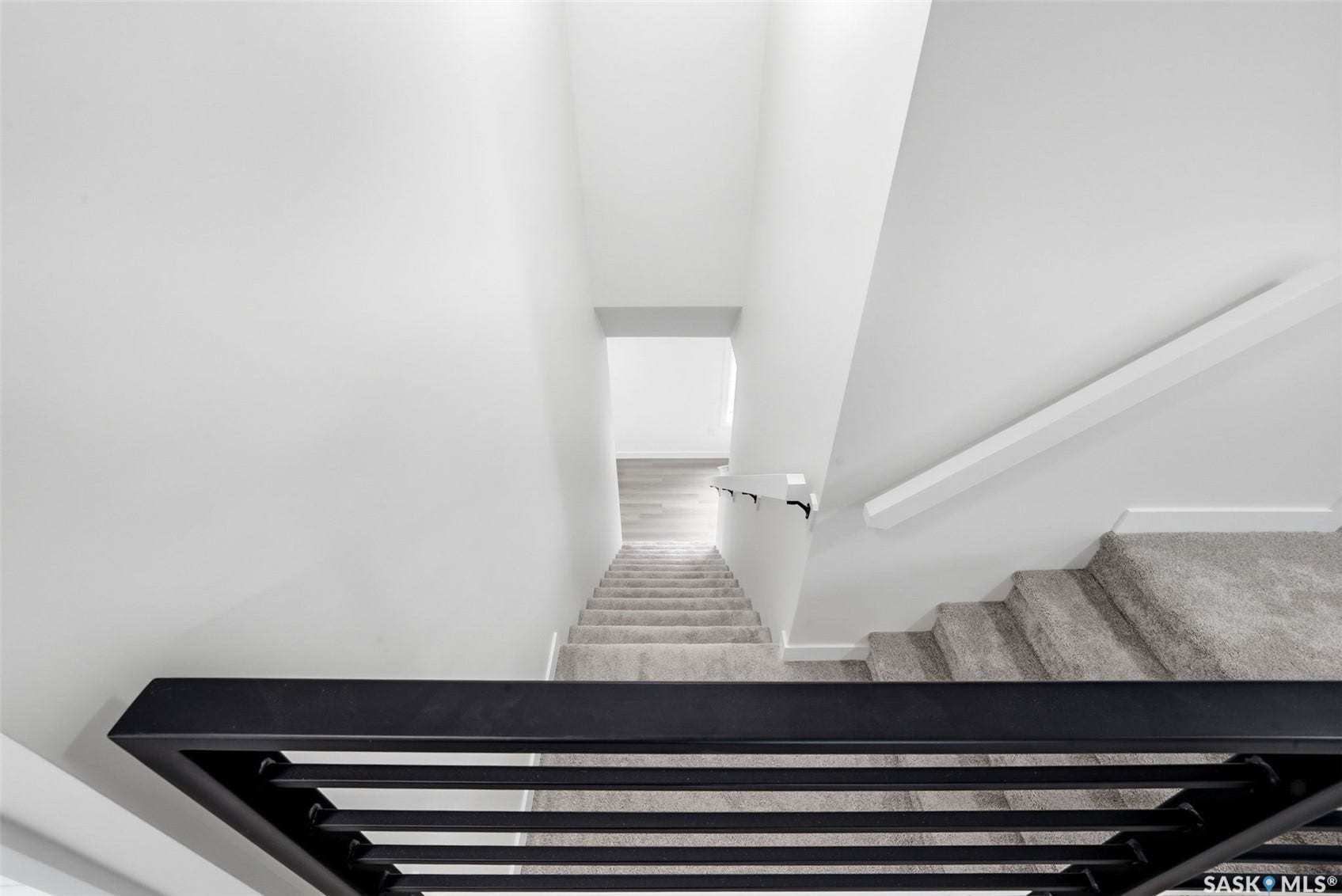 Grey carpeted stairs, white handrail, and matte black metal railing