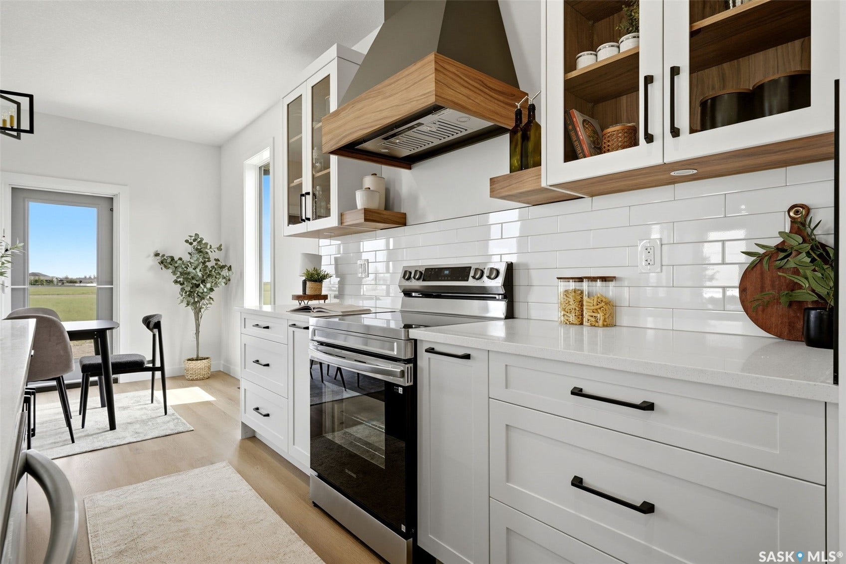 Modern kitchen featuring white cabinetry, light countertops, wood-finish flooring, a stainless steel range, and a subway tile backsplash