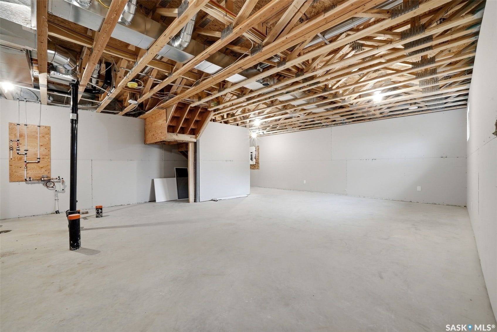 Unfinished basement with concrete flooring, exposed wood ceiling joists, and drywall-ready wall surfaces