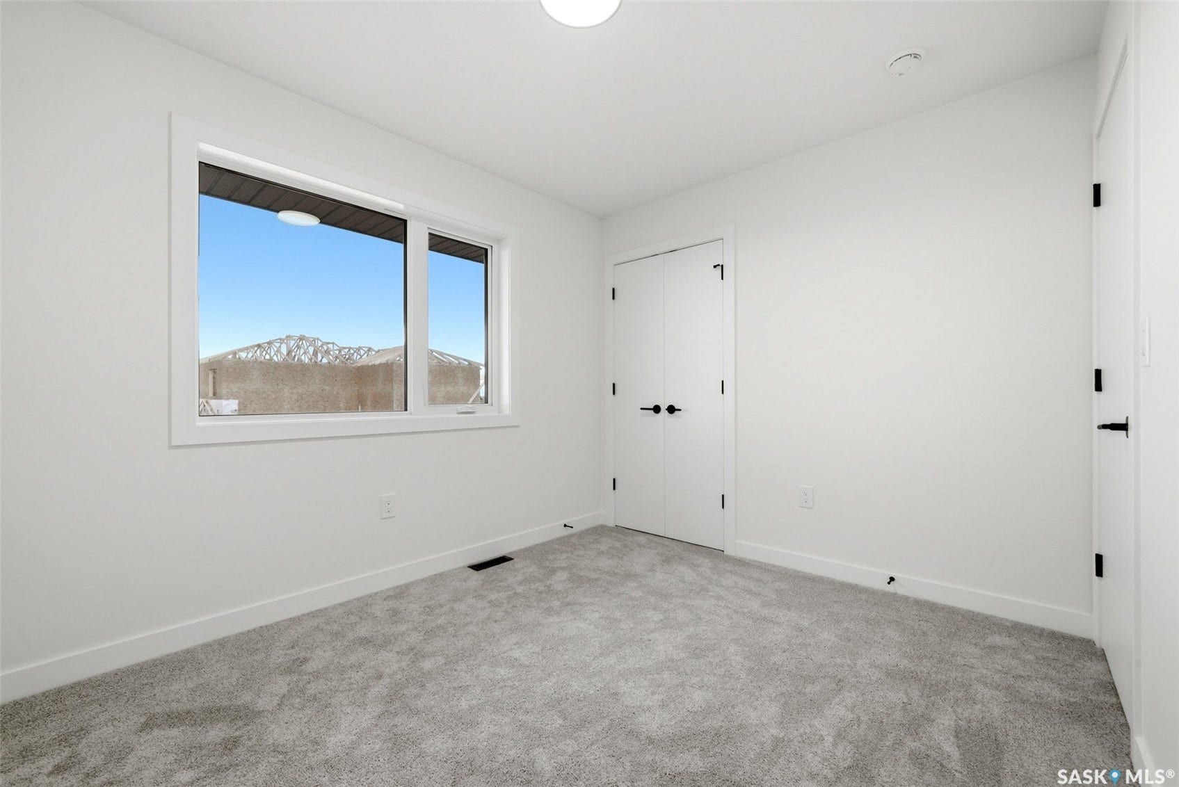 Bright interior with white walls, light gray carpet, and a large window featuring a mountainous backdrop