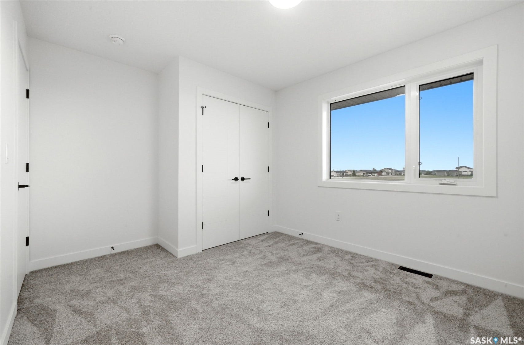 White walls, light gray carpet, and a large window