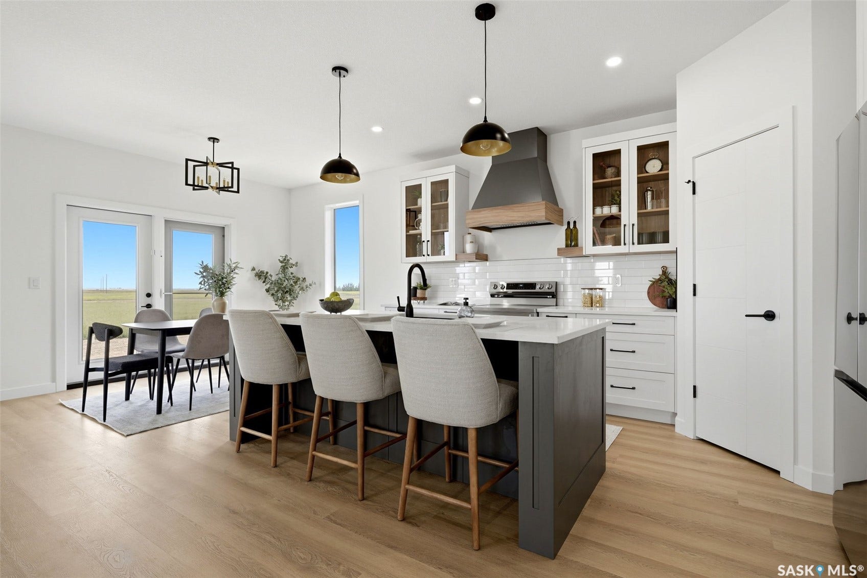 Kitchen featuring an island with seating, pendant lighting, stainless steel appliances, white subway tile backsplash, and light wood-finish flooring
