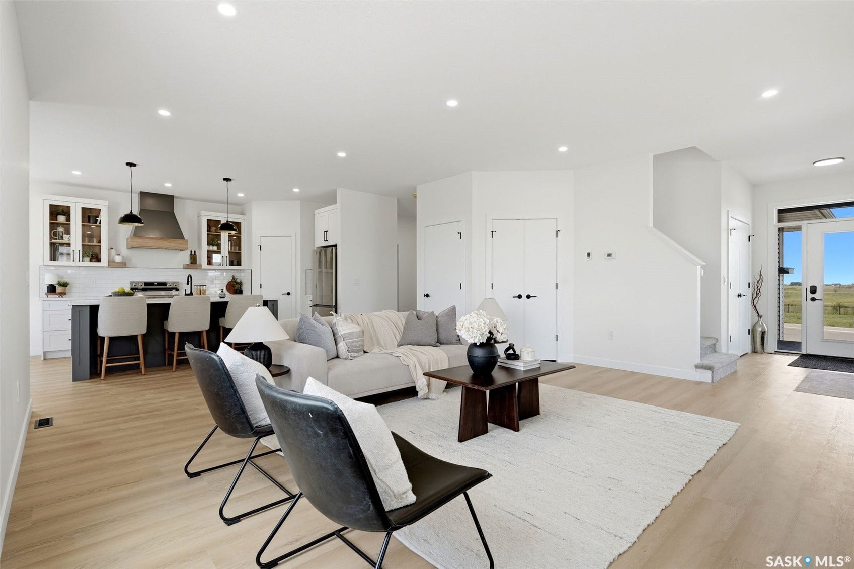 Open-concept living space featuring light wood-finish flooring, recessed lighting, and a white color palette