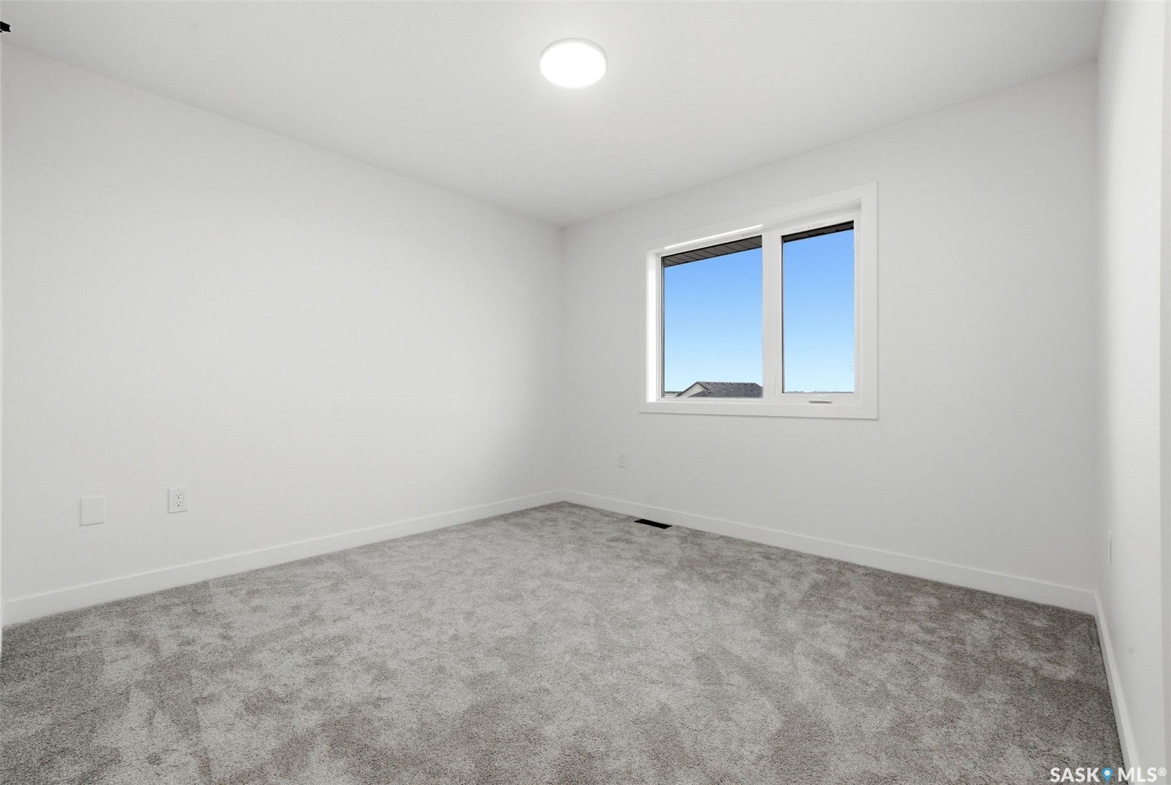 Neutral white walls, plush gray carpeting, modern flush-mount lighting, and a dual-pane window