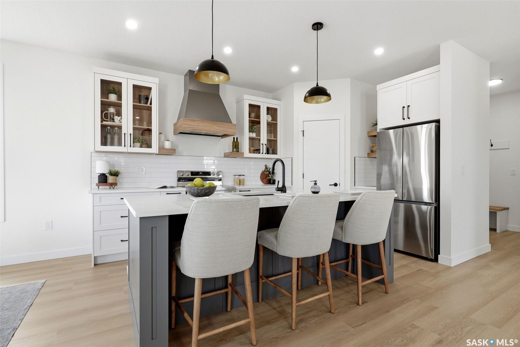 Gourmet kitchen featuring a central island with seating, stainless steel refrigerator, white subway tile backsplash, recessed lighting, and wood-finish flooring