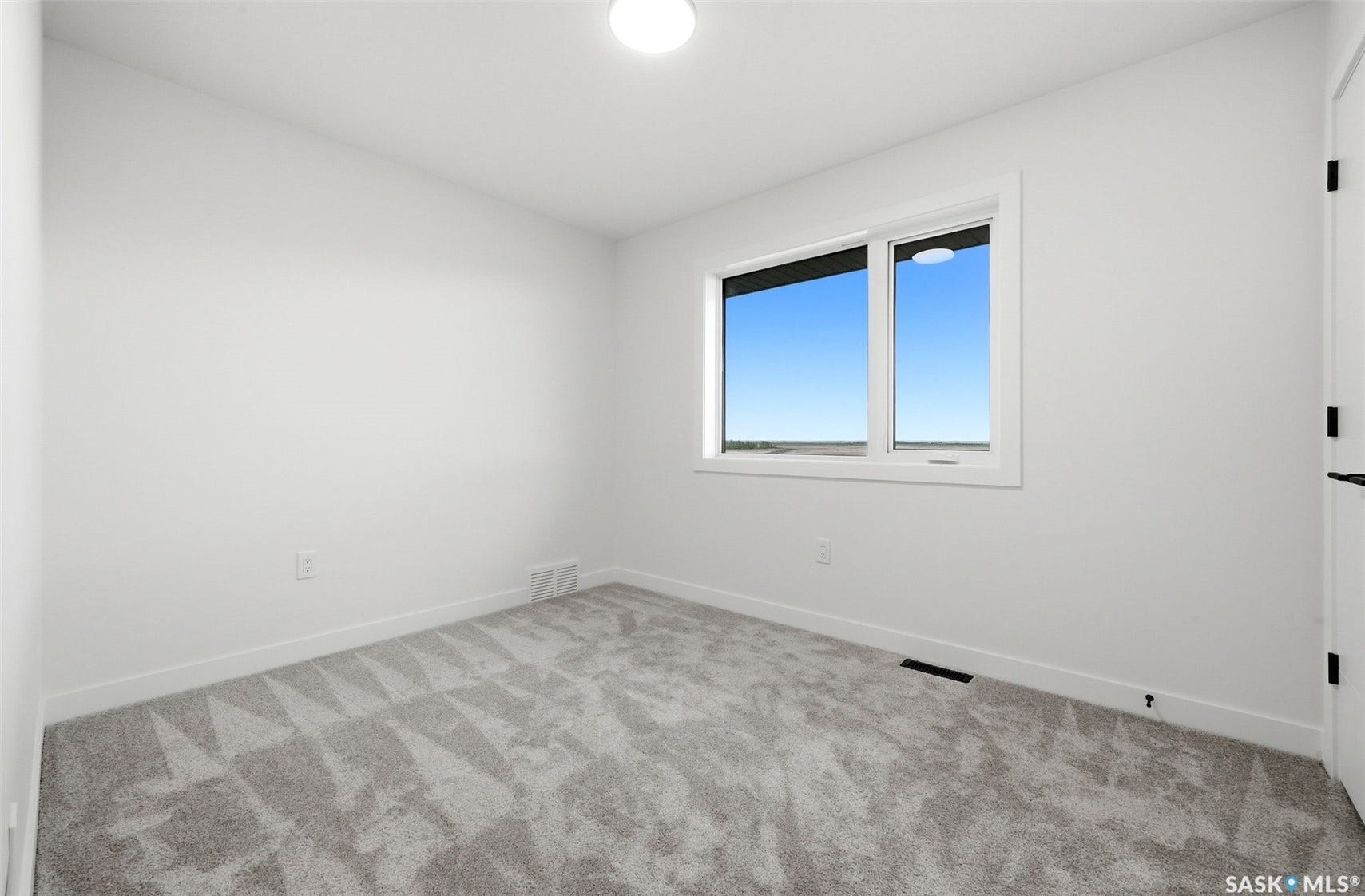 Neutral wall paint, textured gray carpeting, and a white-framed window