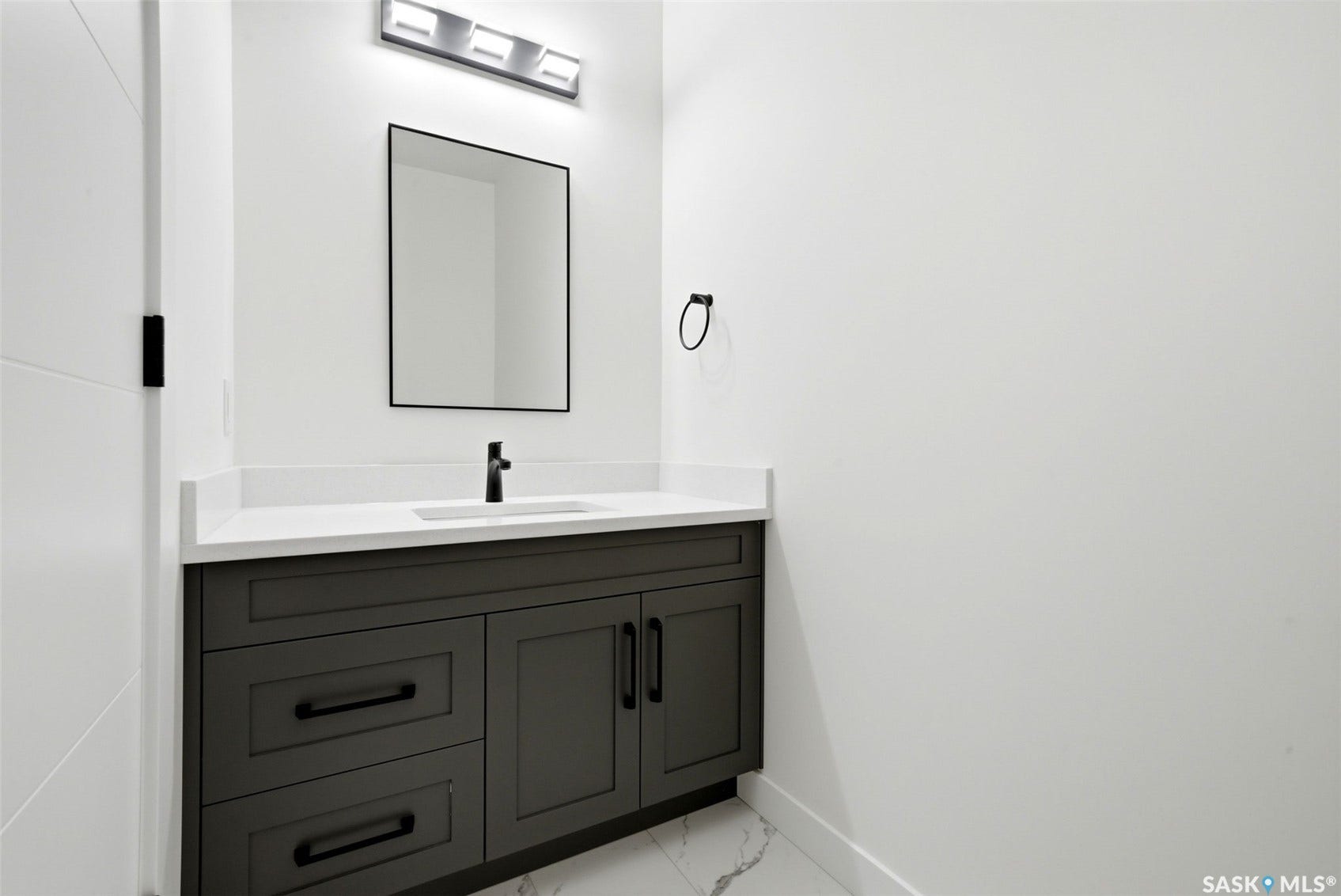 Floating vanity with a white countertop and integrated sink, matte black faucet, and a rectangular mirror
