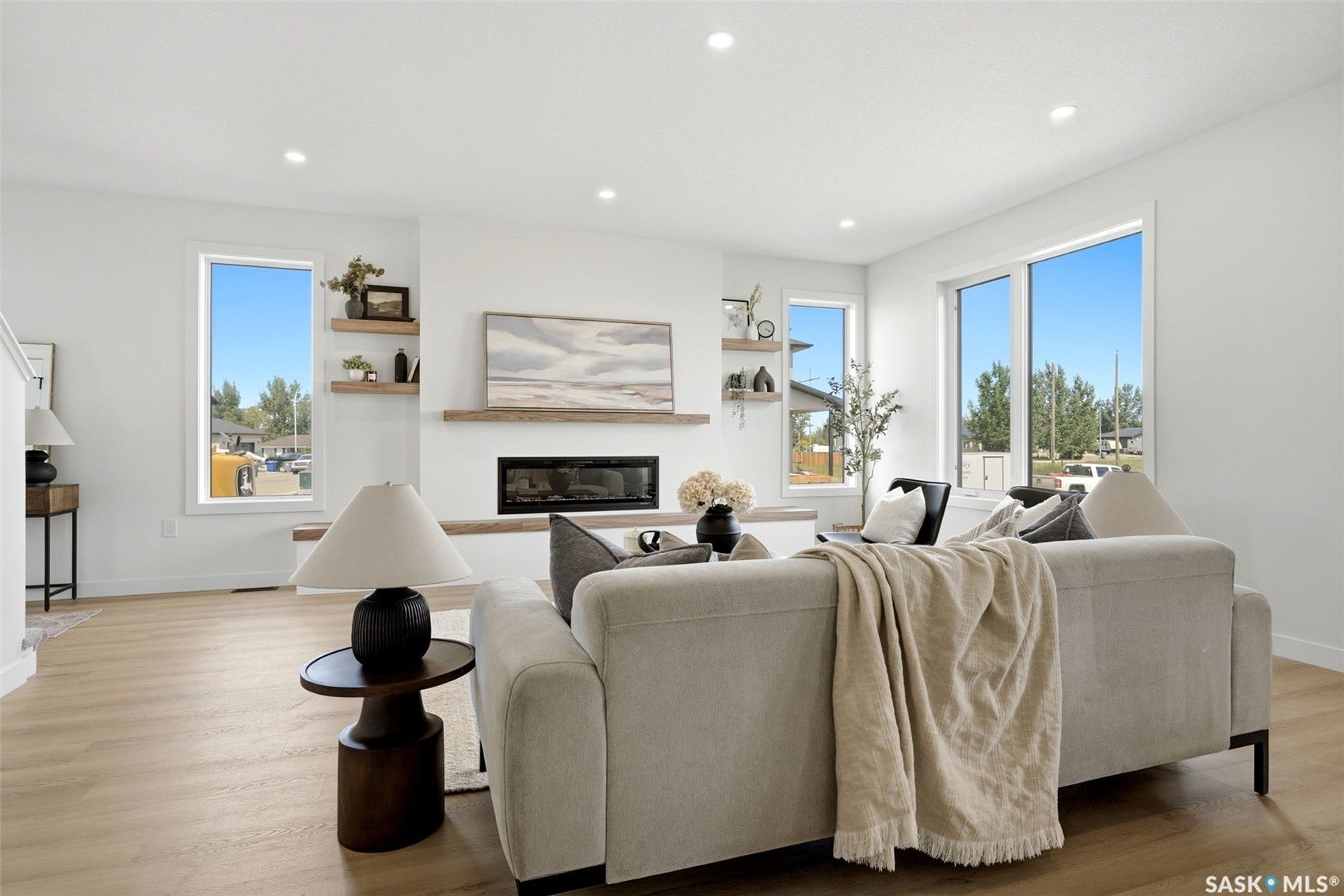 Spacious living area featuring light wood-finish flooring, recessed lighting, and large windows