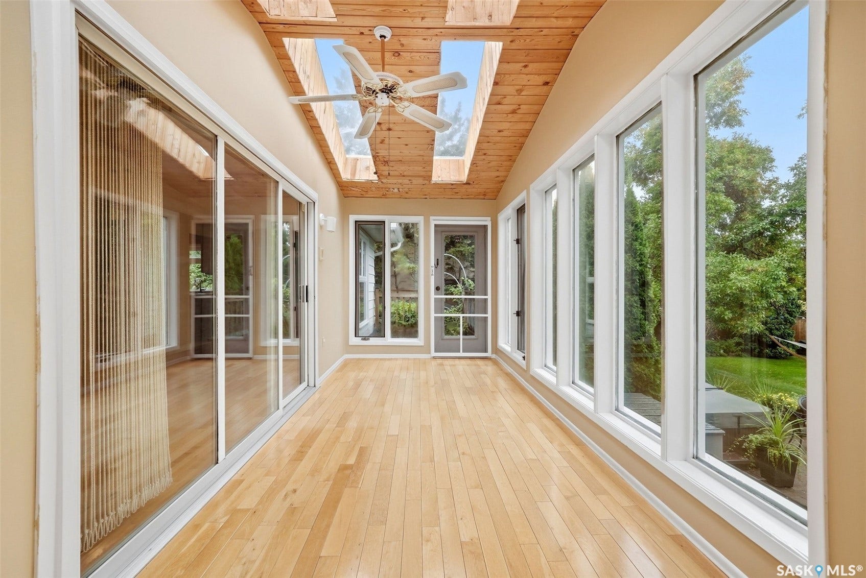 Sunroom with wood-finish flooring, a natural wood paneled ceiling, and multiple skylights