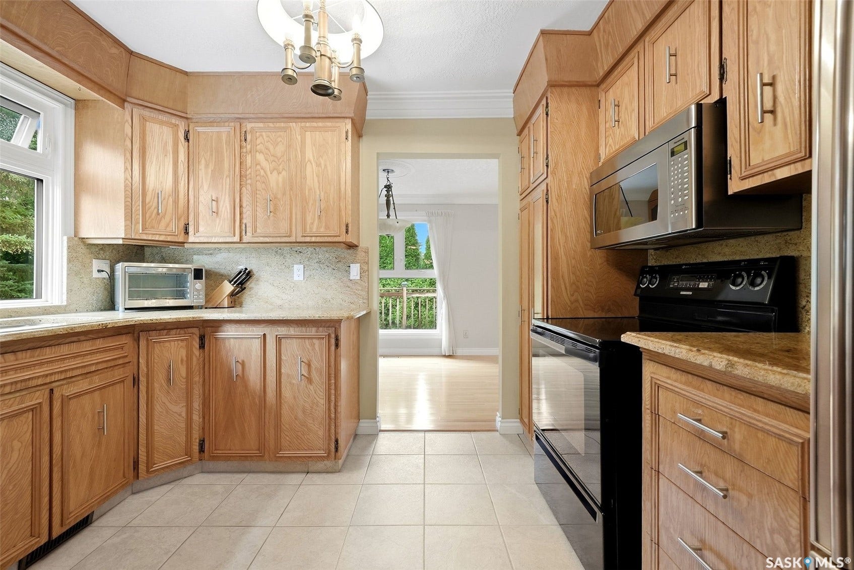 Kitchen featuring wood-finish cabinetry, light-toned countertops, tile flooring, and integrated stainless steel appliances