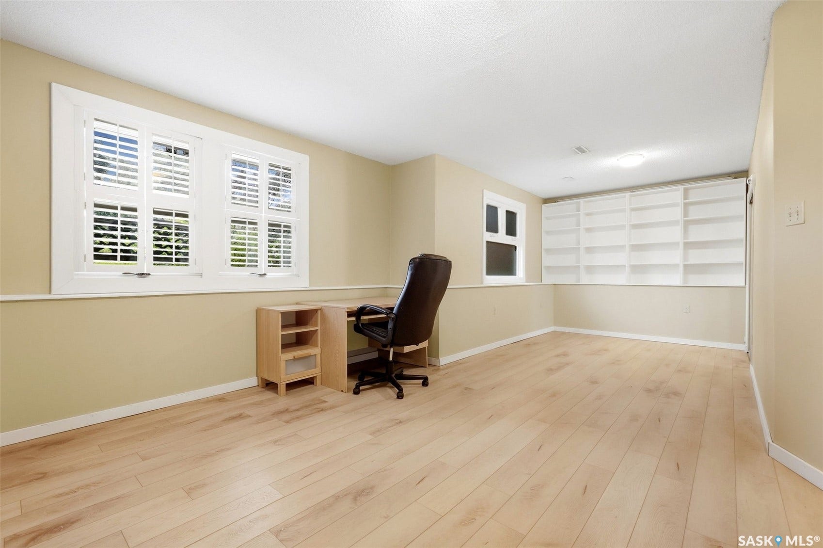 Light wood-finish flooring, built-in shelving, and two distinct window styles