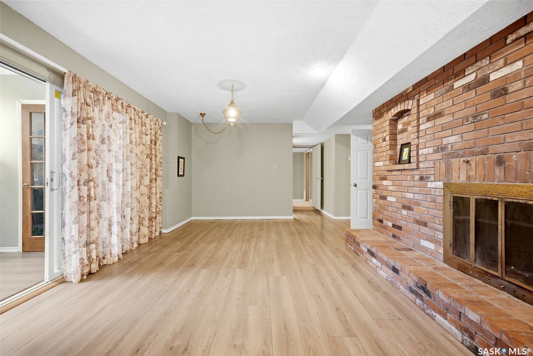 Brick fireplace, wood-finish flooring, sliding glass door, recessed lighting, and suspended ceiling fixture
