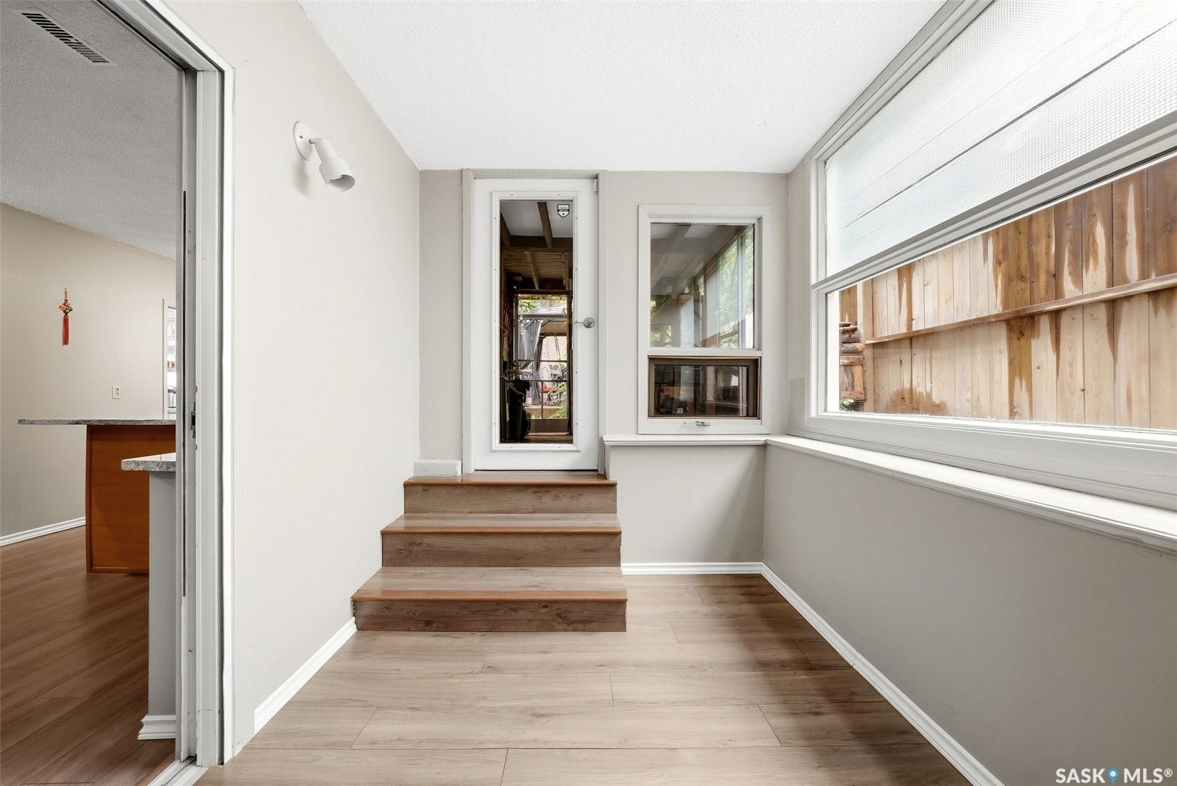Wood-finish flooring, multiple windows, sliding glass door, and a built-in light fixture