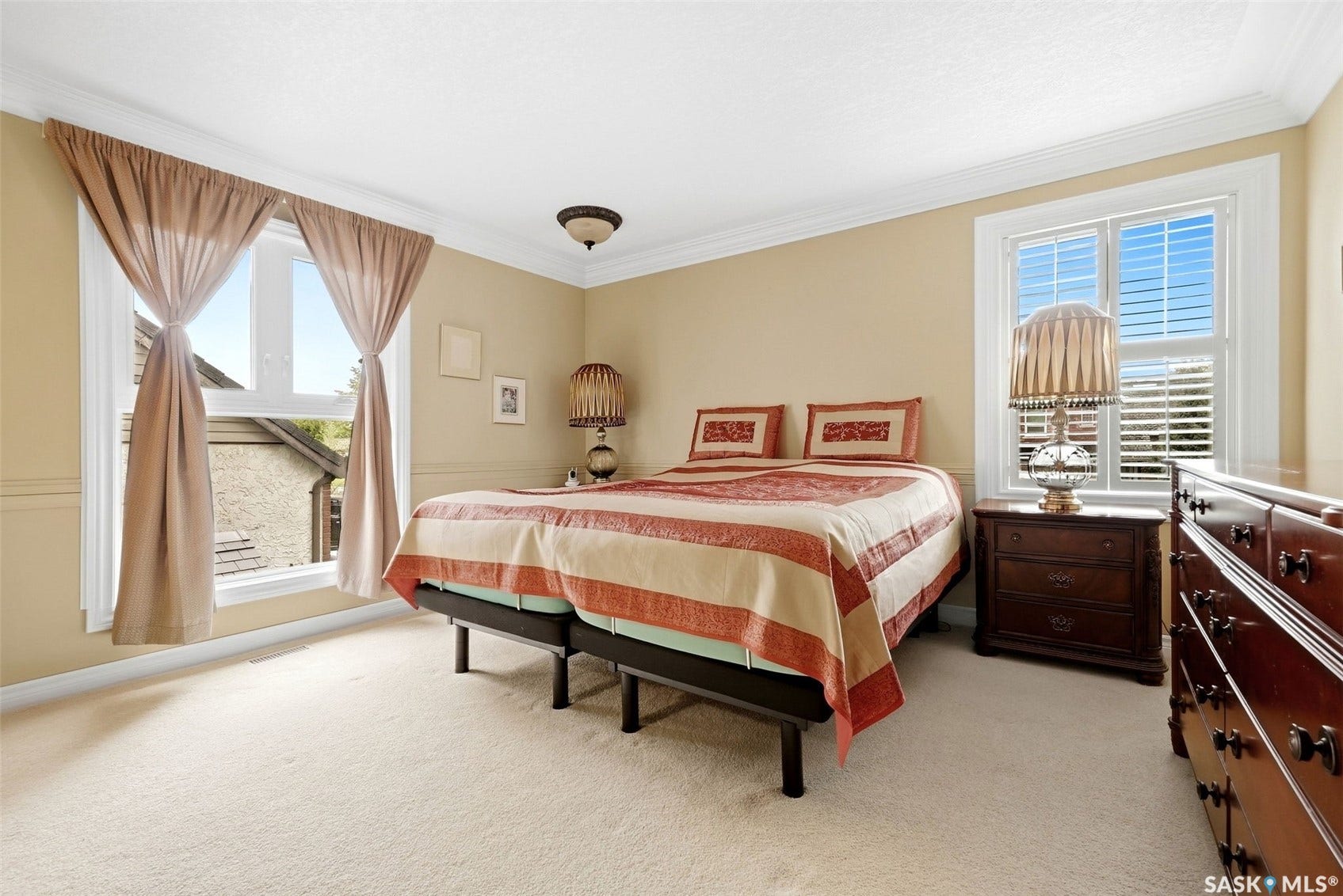 Neutral tone wall paint, crown molding, double windows, wall paneling, and carpet flooring