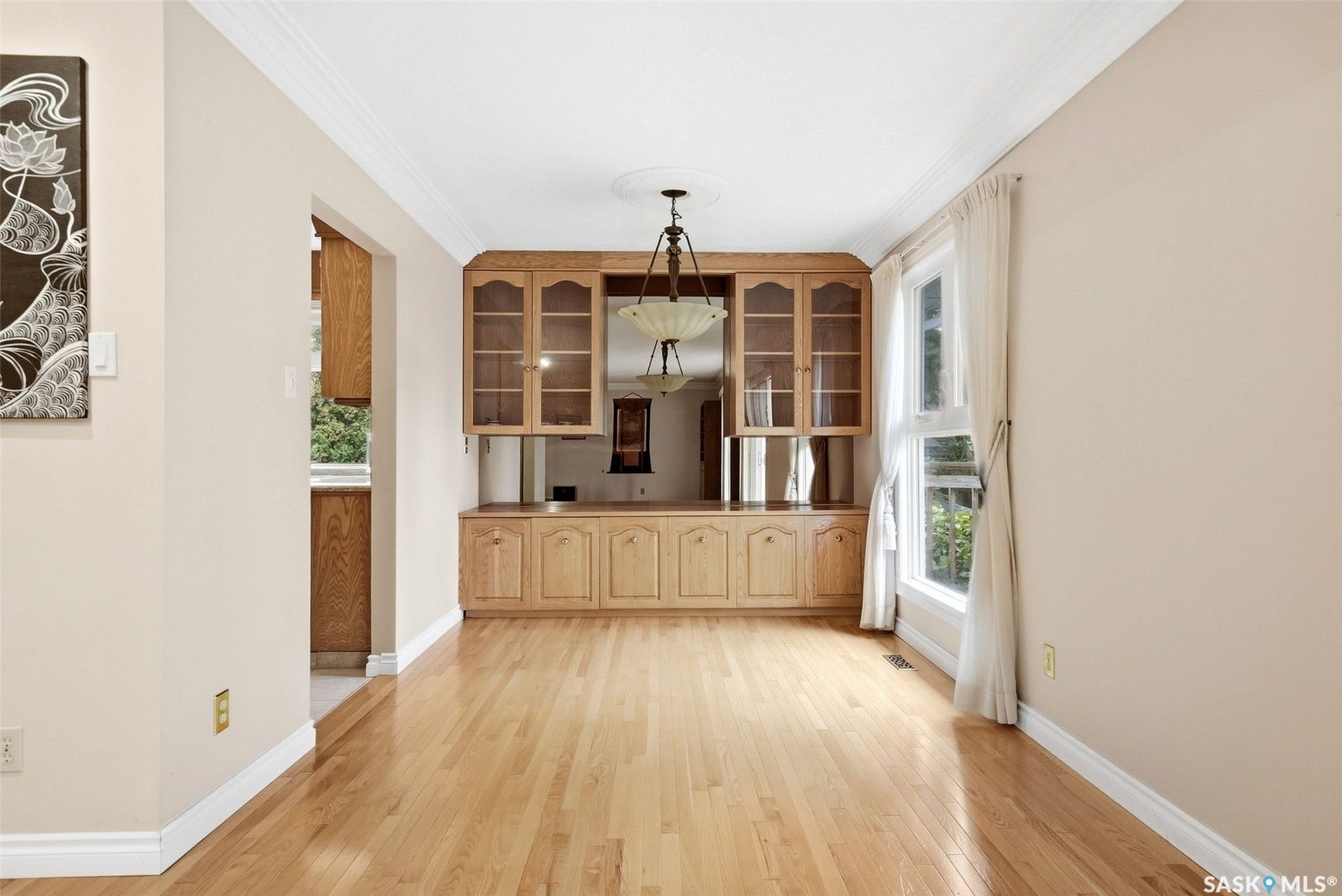 Built-in cabinetry with glass-front uppers, hardwood flooring, and crown molding