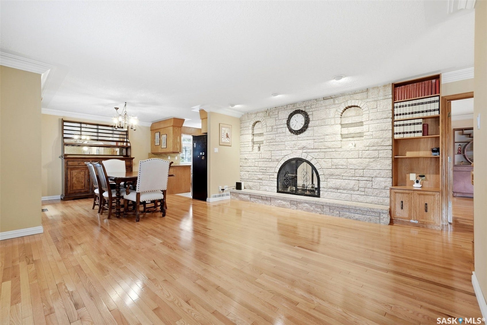 Hardwood flooring, stone-clad fireplace, integrated shelving, crown molding, and a built-in dining area hutch
