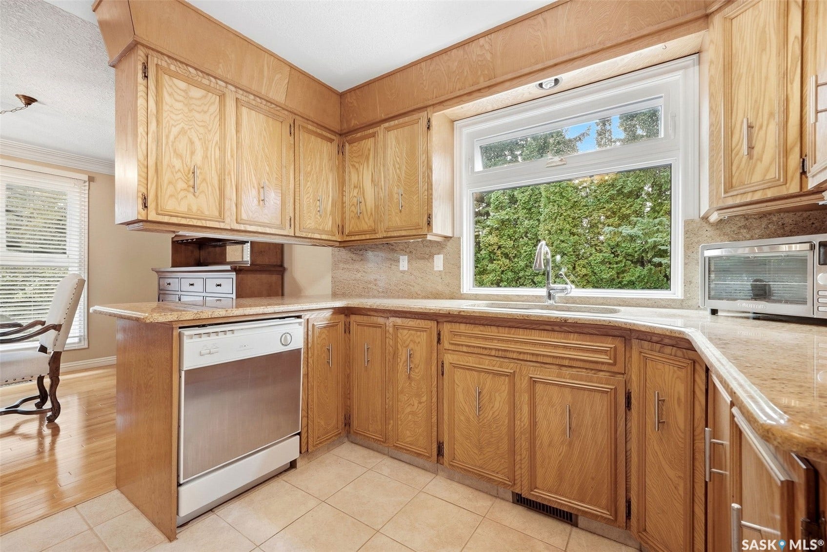 Kitchen featuring wood cabinetry, stone countertops, a tiled backsplash, and a stainless steel sink with a window