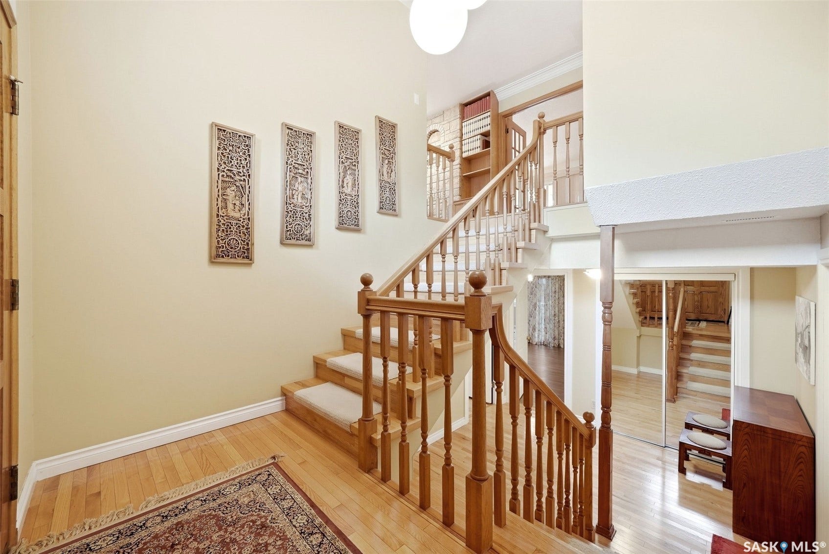 Grand foyer with wood-finish flooring, a multi-level staircase with wood balusters, and a built-in shelving unit