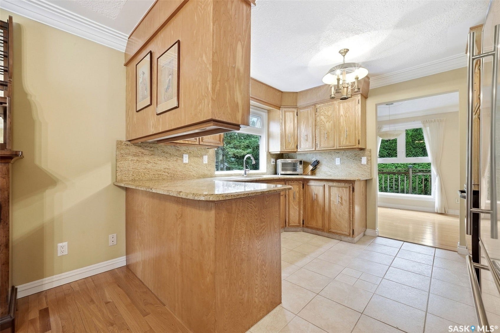 Kitchen featuring wood cabinetry, light-toned countertops, tile flooring, and a window above the sink
