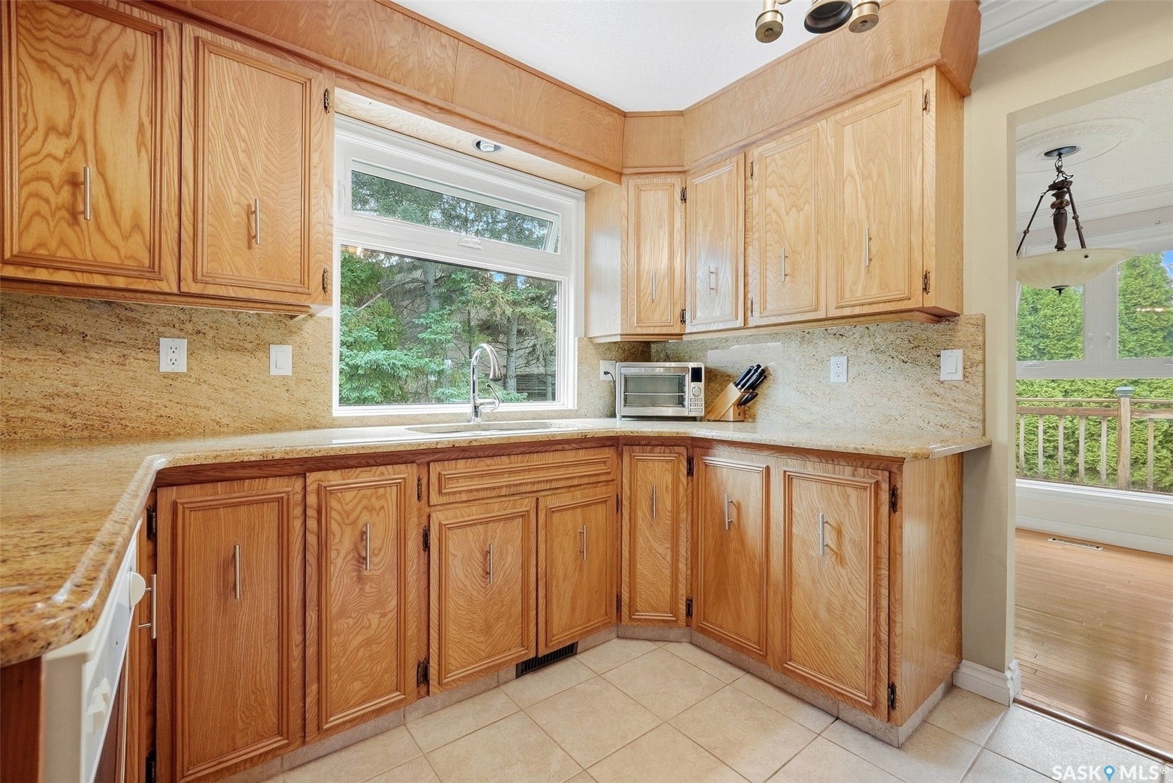 Wood-finish cabinetry, light-toned countertops, tile flooring, and a stainless steel sink