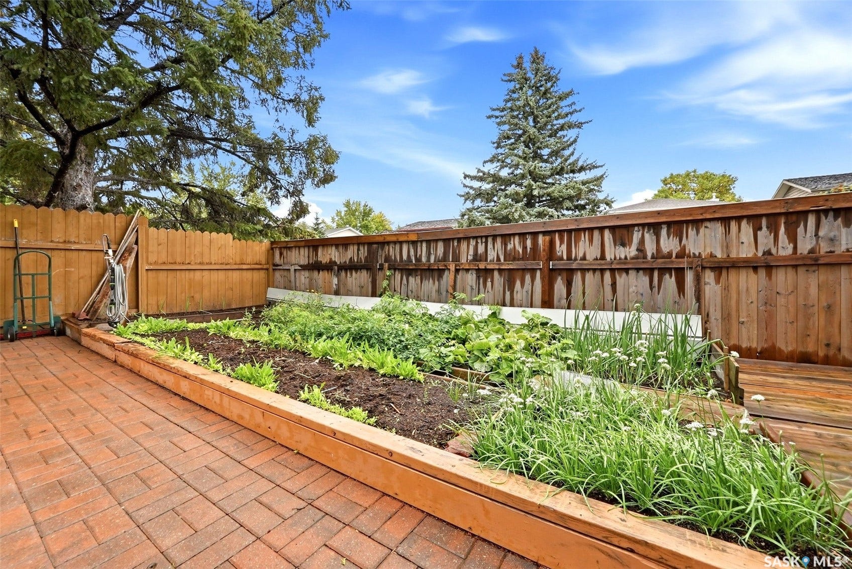 Brick paver patio with a wood-framed raised garden bed, wood privacy fencing, and wood decking