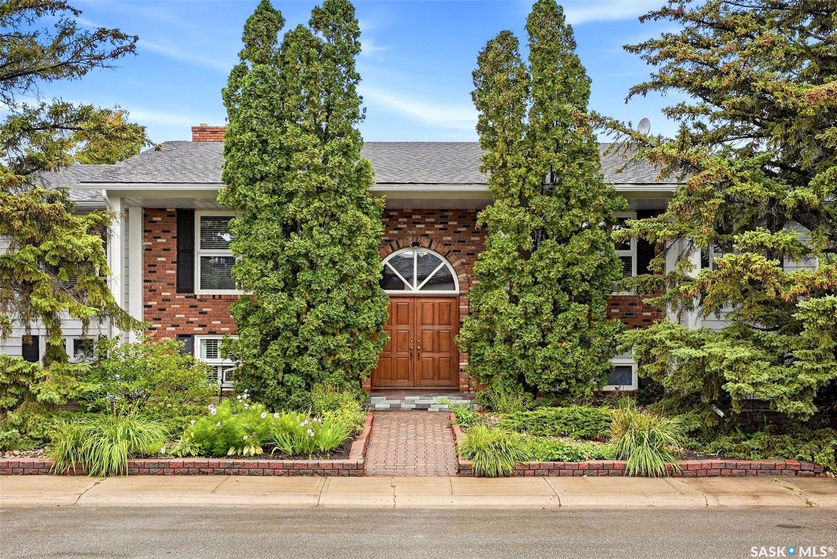Brick facade with white siding accents, an arched entry door, and a gabled roof