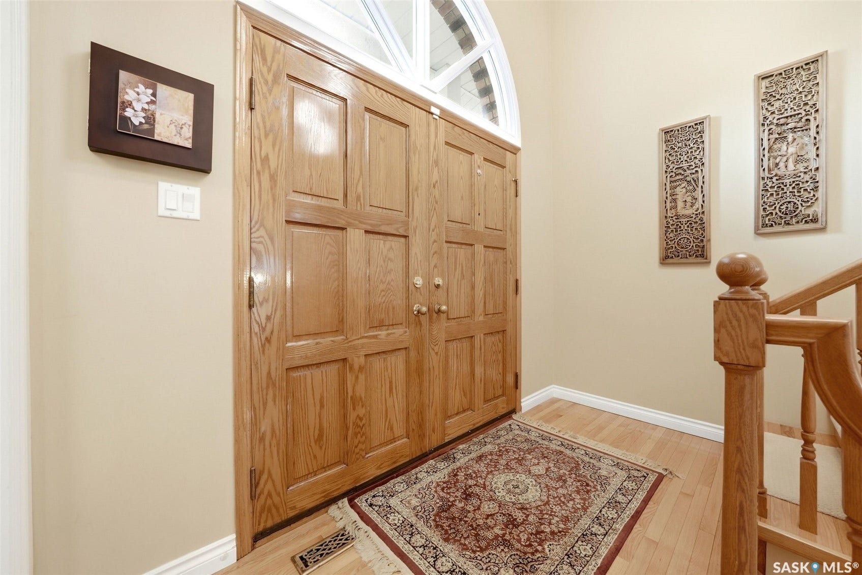 Double wood-paneled entry doors with an arched transom window