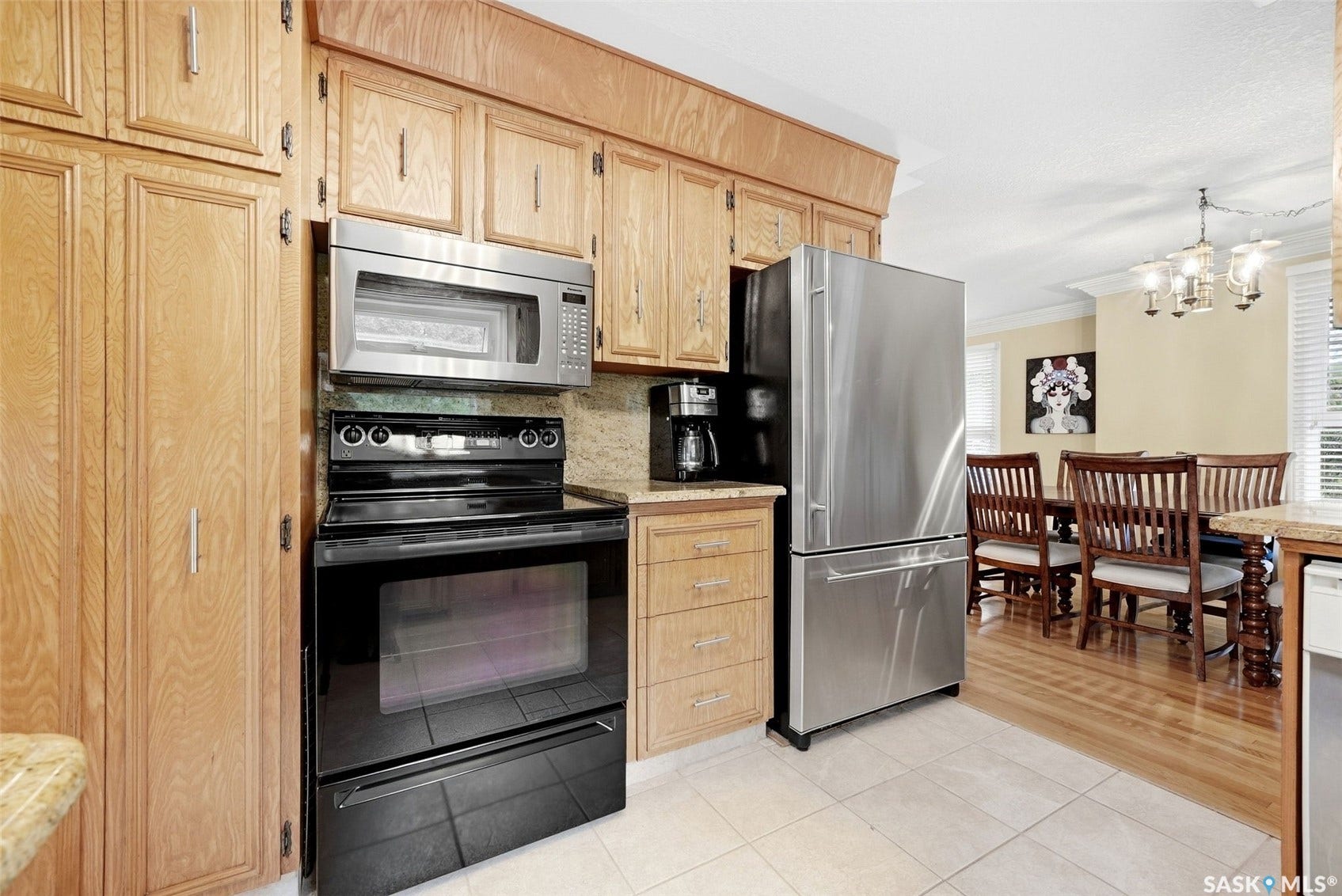Kitchen featuring wood cabinetry, stainless steel appliances, tiled flooring, and stone countertops