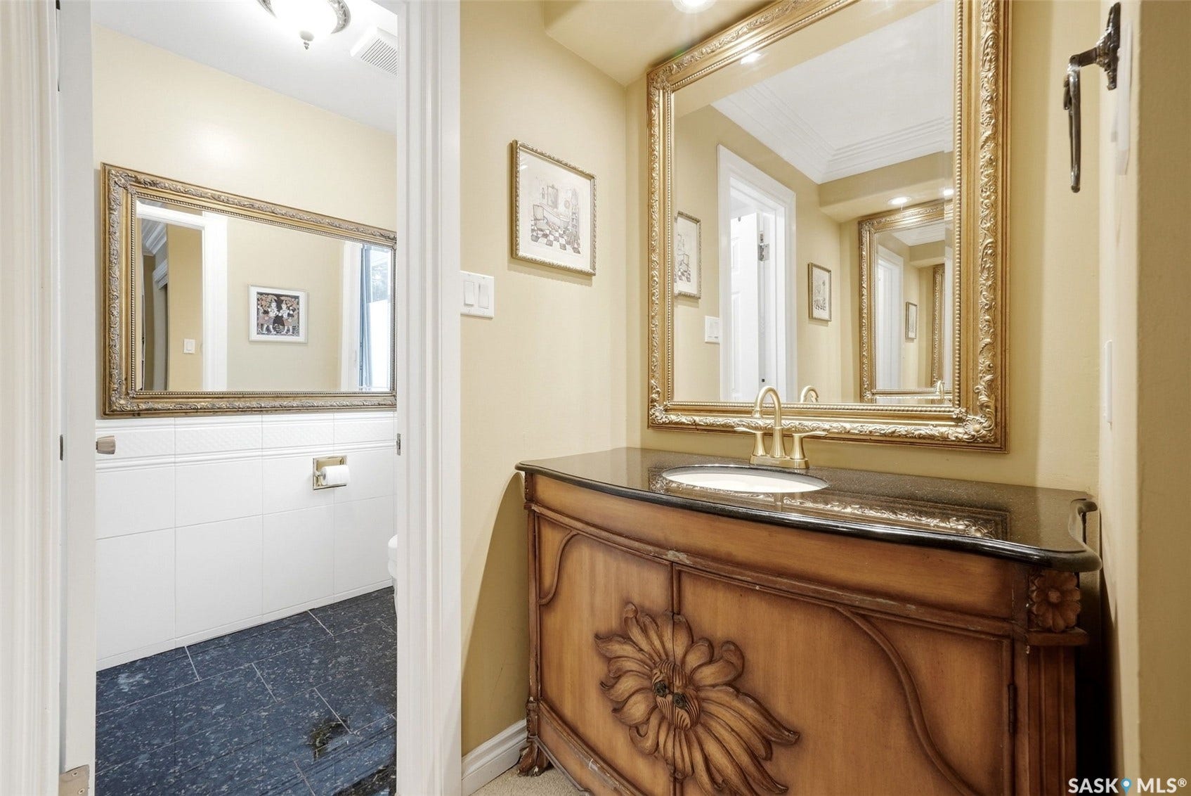 Custom vanity with carved details, dark countertop, and integrated sink