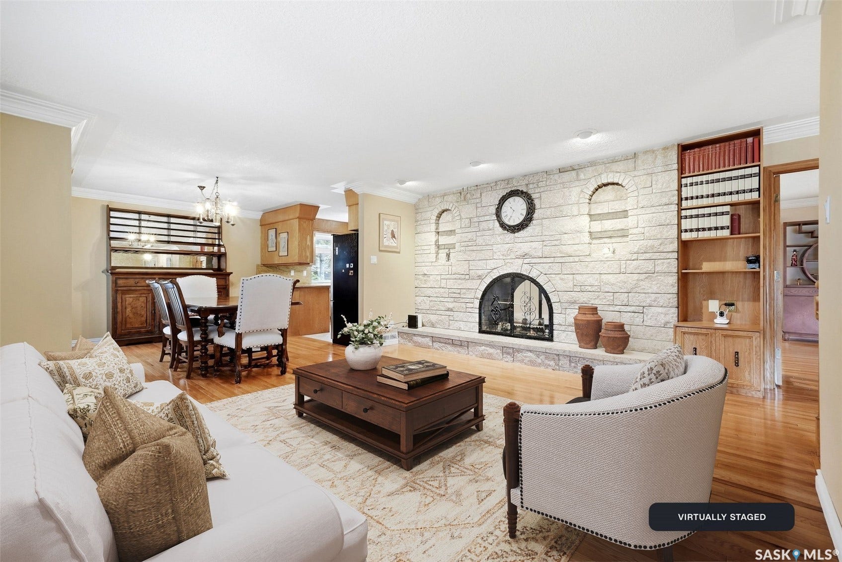 Stone-clad fireplace with arched opening, built-in shelving, wood-finish flooring, and crown molding