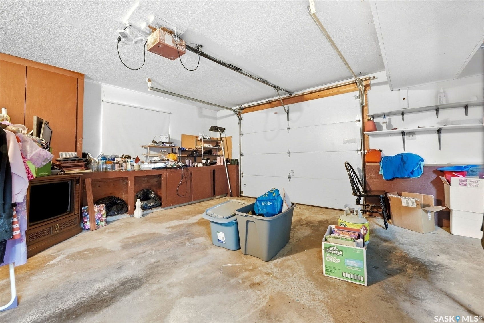 Attached garage with a sectional overhead door, built-in cabinetry, wall shelving, and a concrete floor