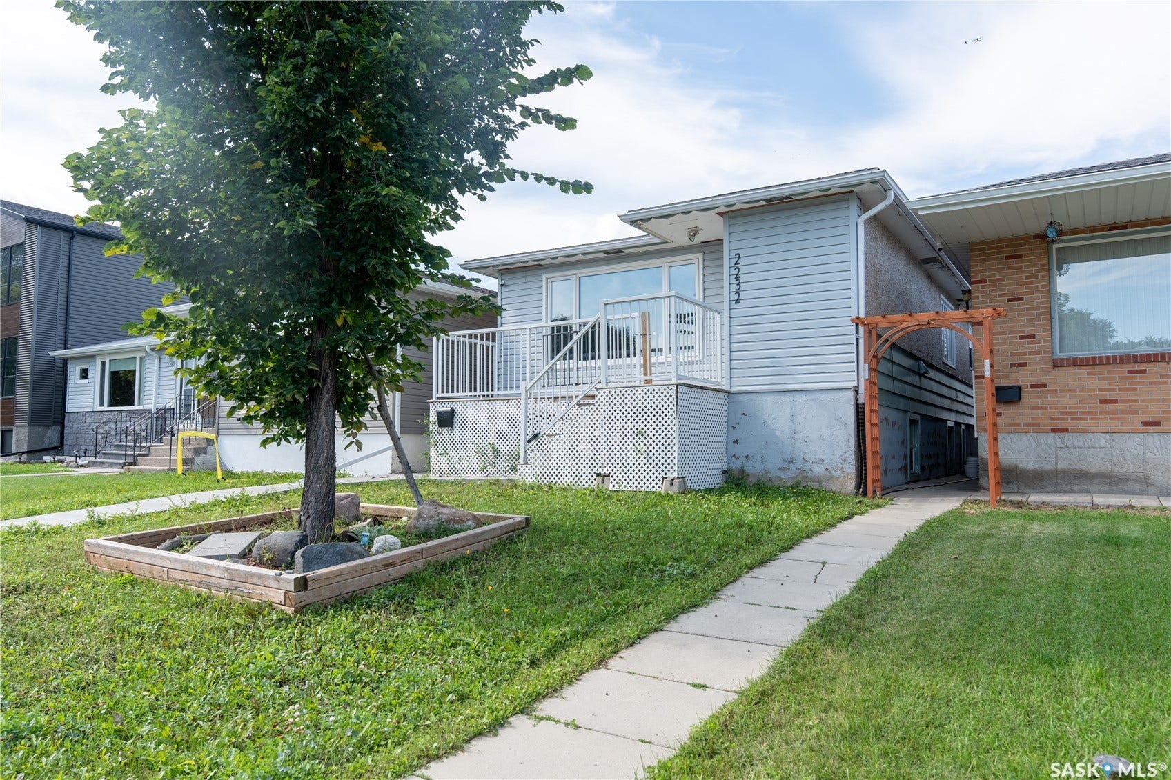 2232 McAra Street, Regina SK S4N 2W1 Siding exterior with a front deck, white railing, and a ground-level patio
