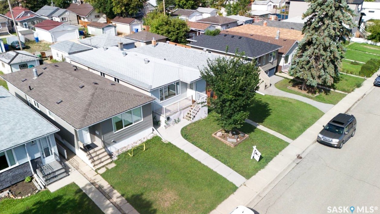 2232 McAra Street, Regina SK S4N 2W1 Manicured front lawn with mature trees, paved sidewalk, and street parking
