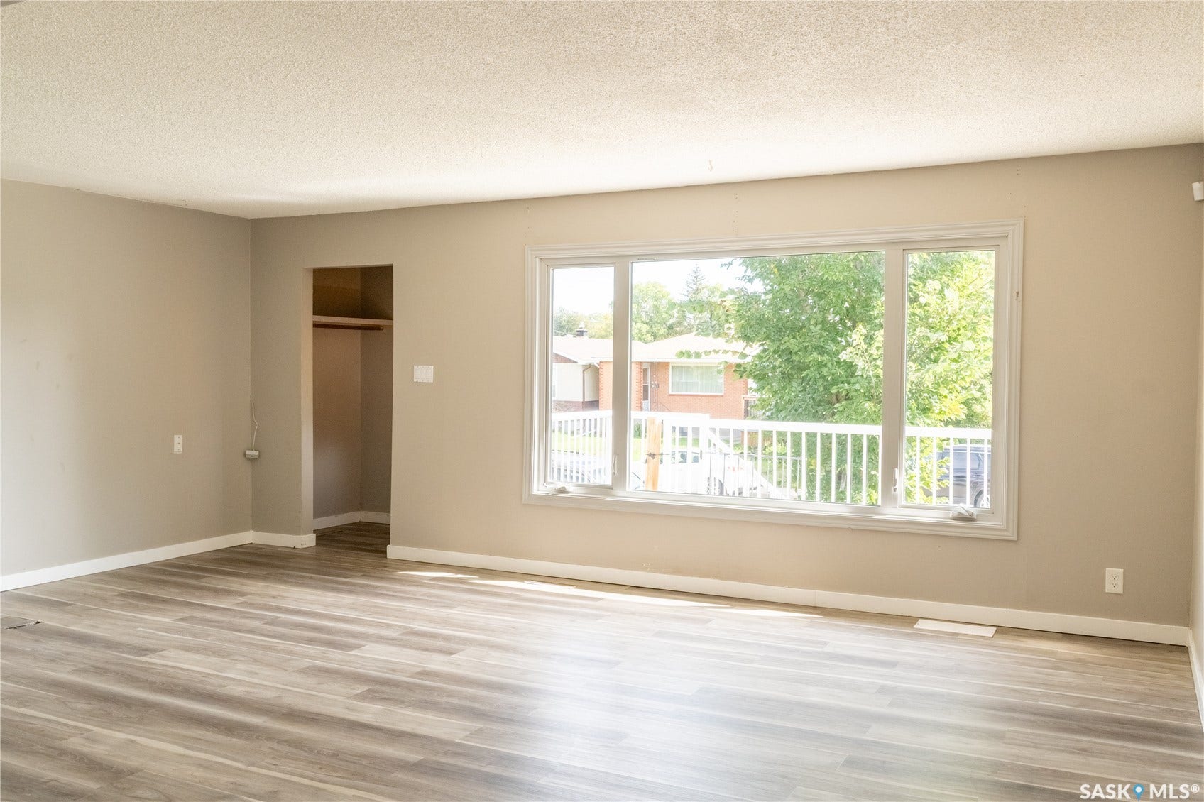 2232 McAra Street, Regina SK S4N 2W1 Spacious interior with wood-finish flooring, neutral wall paint, and a large window