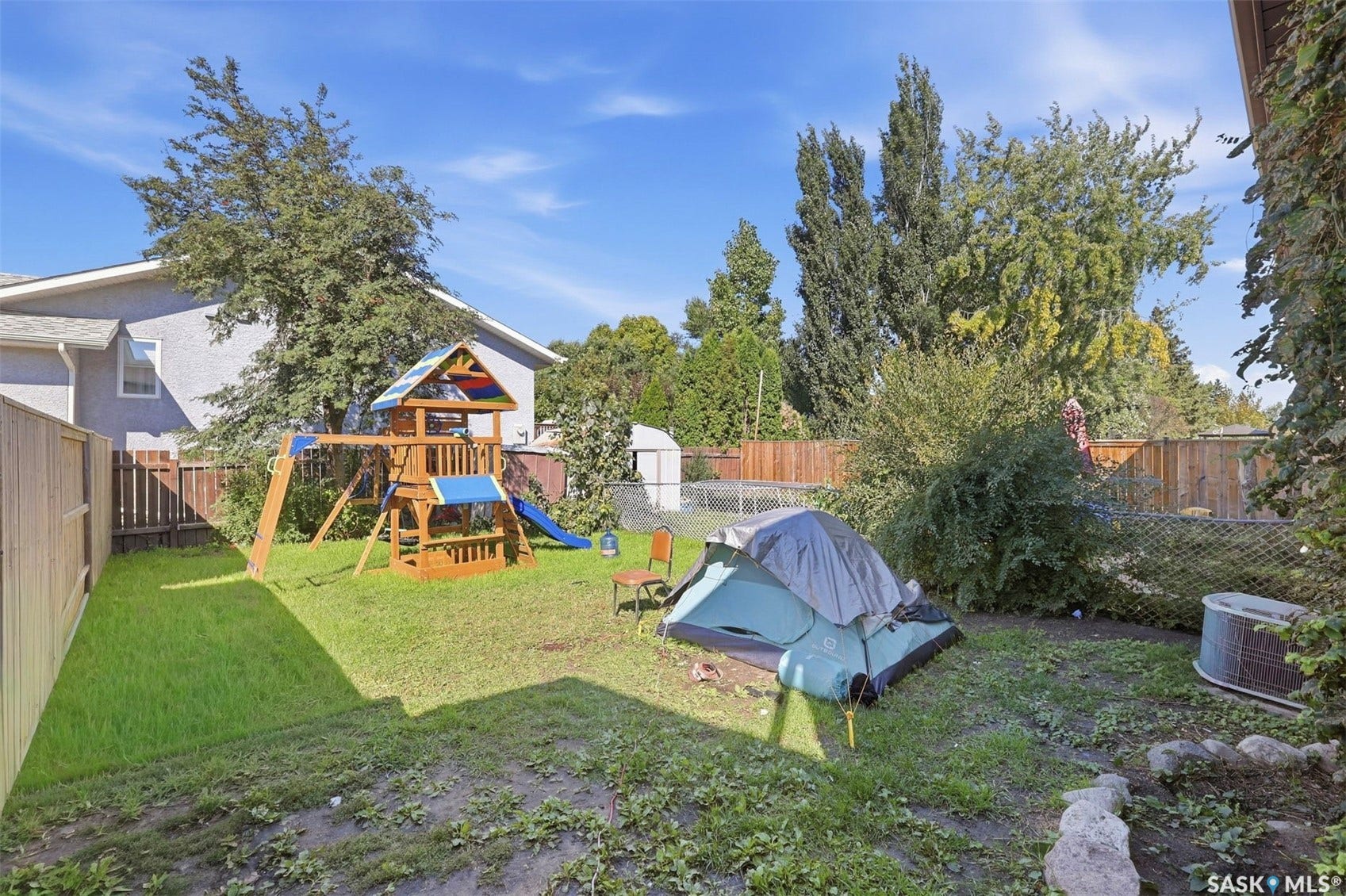 Expansive grassy yard area with a wooden privacy fence