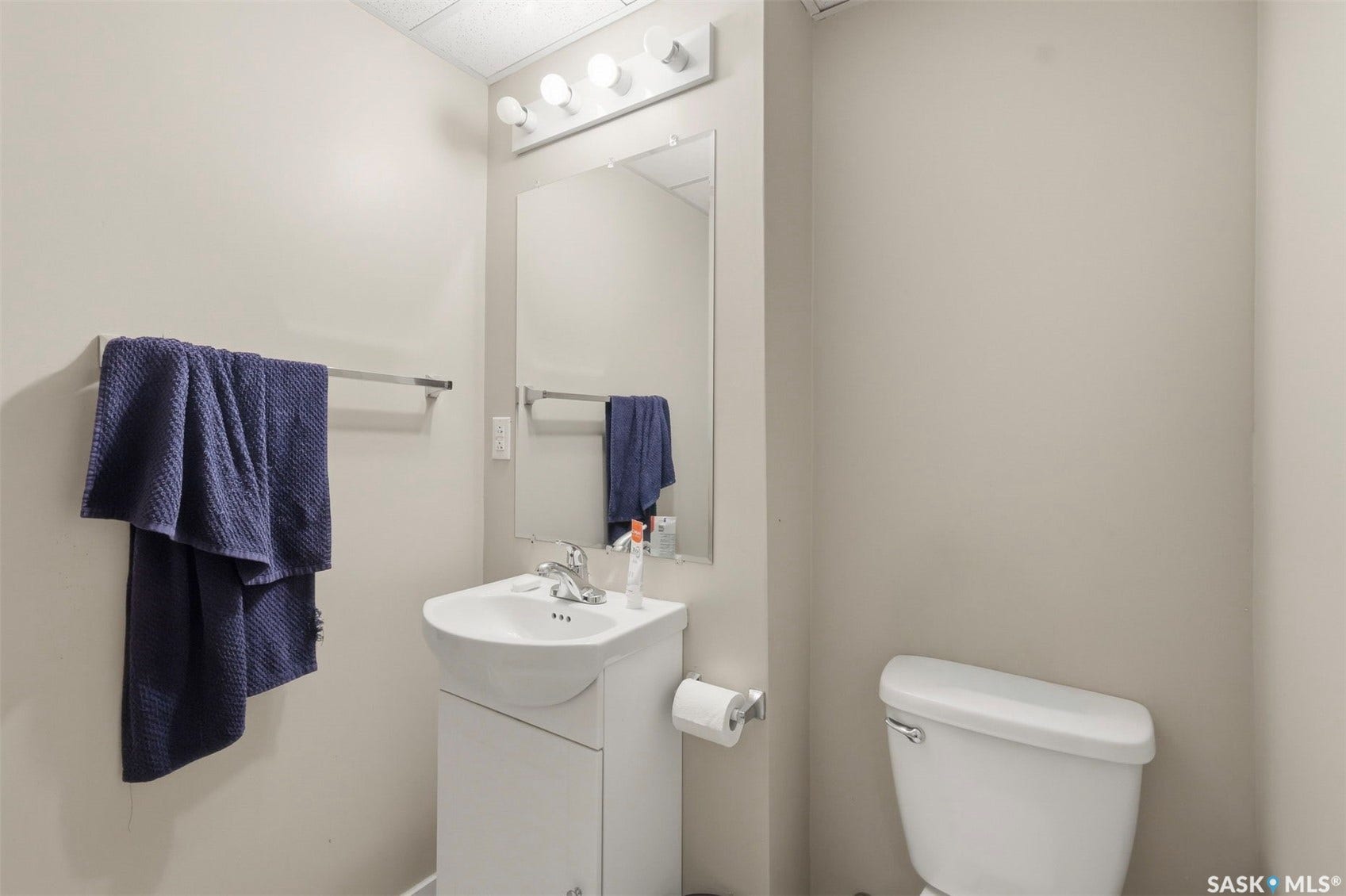 Vanity with integrated sink, chrome faucet, wall-mounted mirror, and overhead vanity lighting