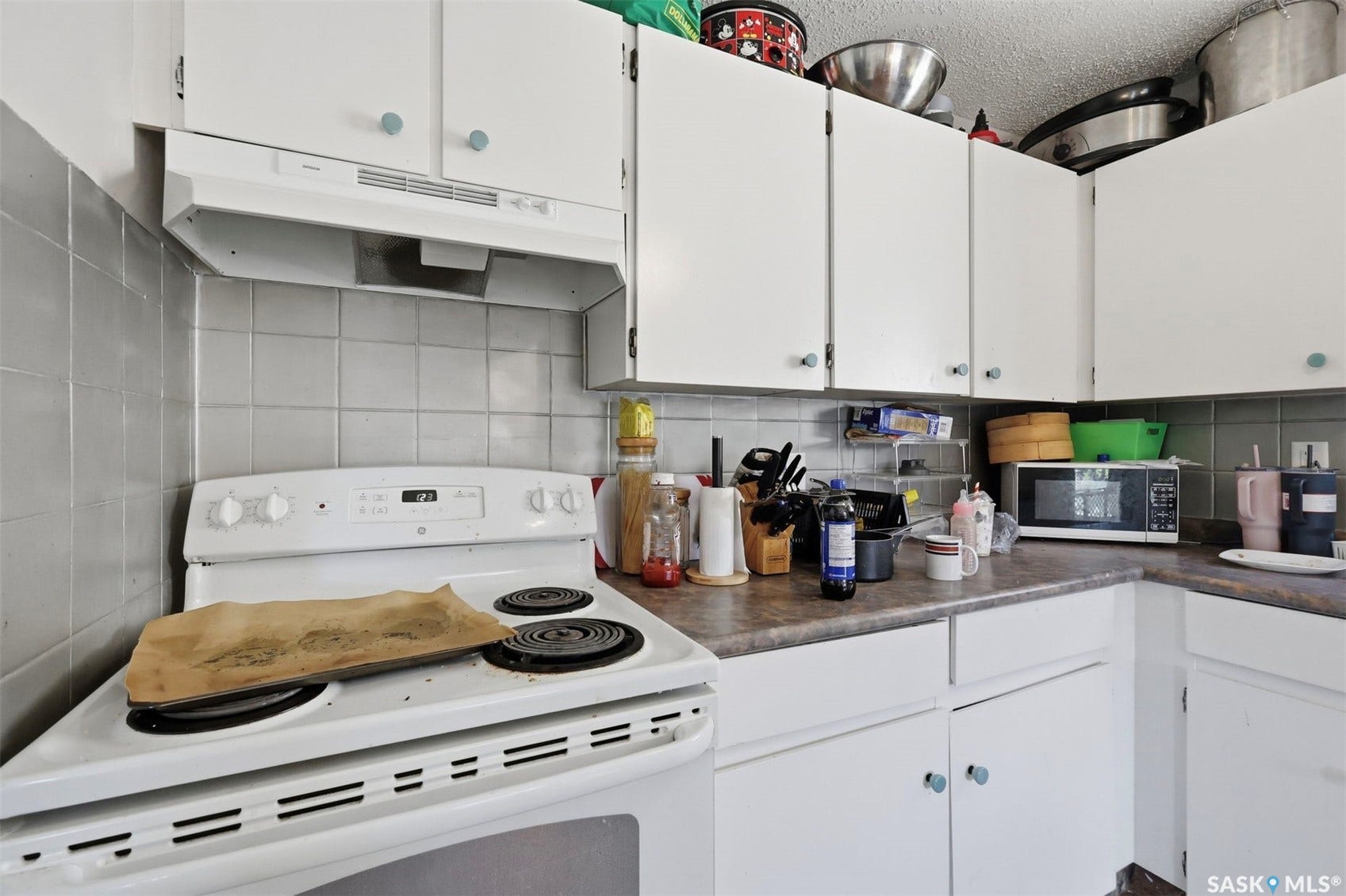 White cabinetry with light blue hardware, white electric range, and gray tiled backsplash