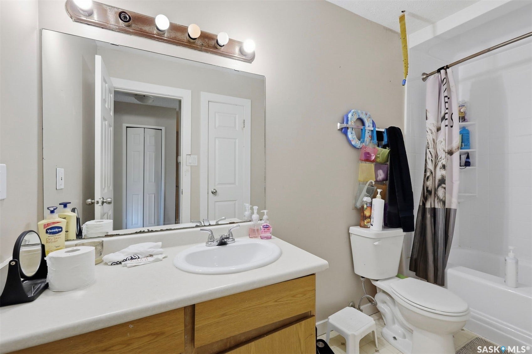 Vanity with integrated sink, wood-finish cabinetry, and overhead bar lighting