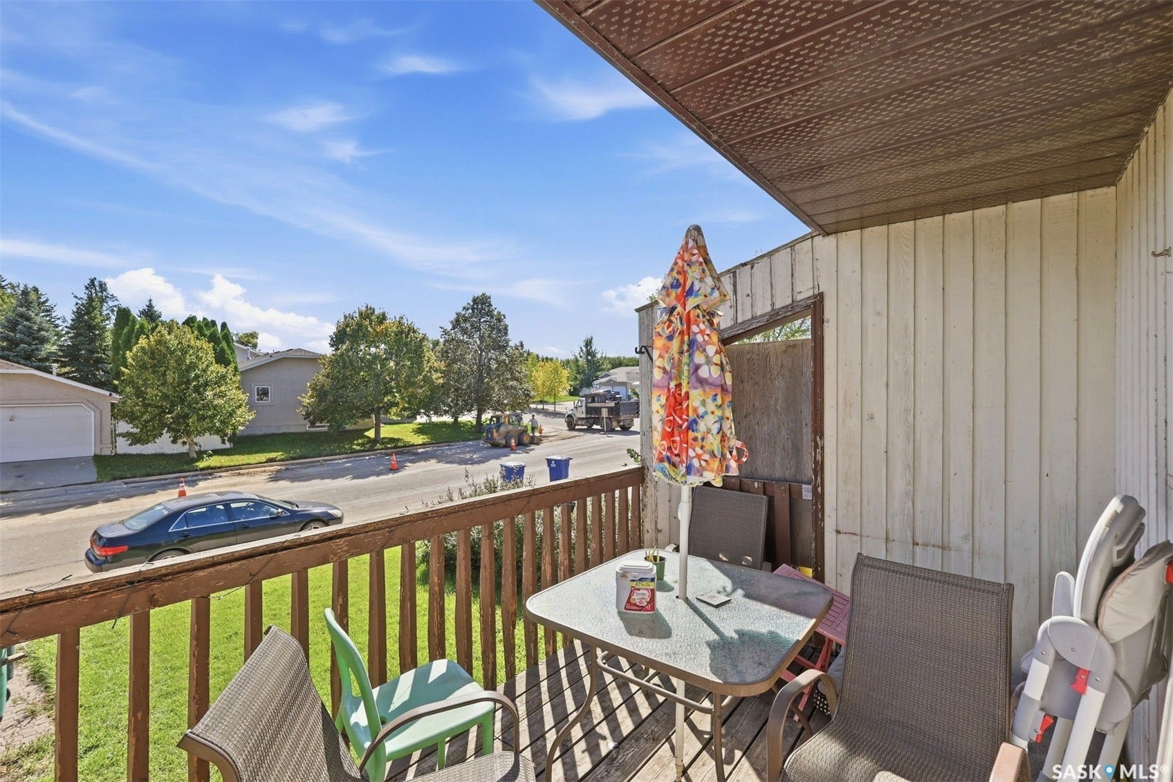 Outdoor balcony with wood railing, textured ceiling, and a light-colored vertical siding exterior