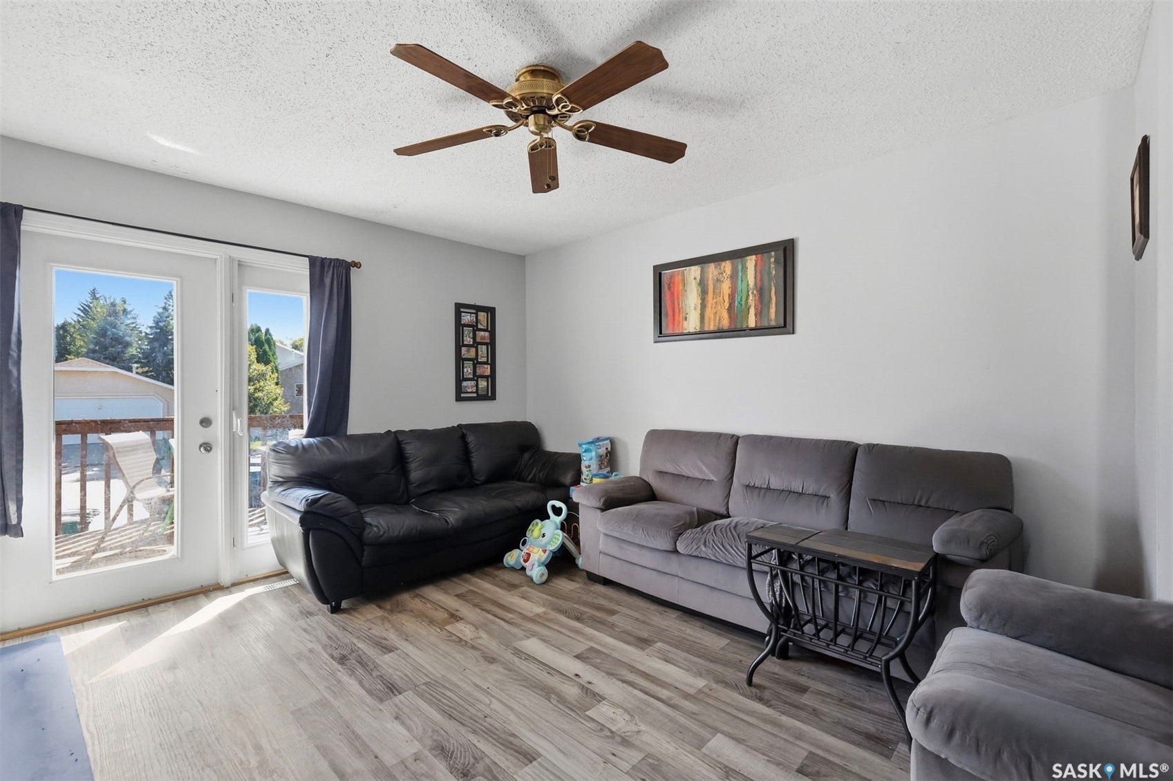 Wood-finish flooring, ceiling fan with integrated lighting, and white walls throughout