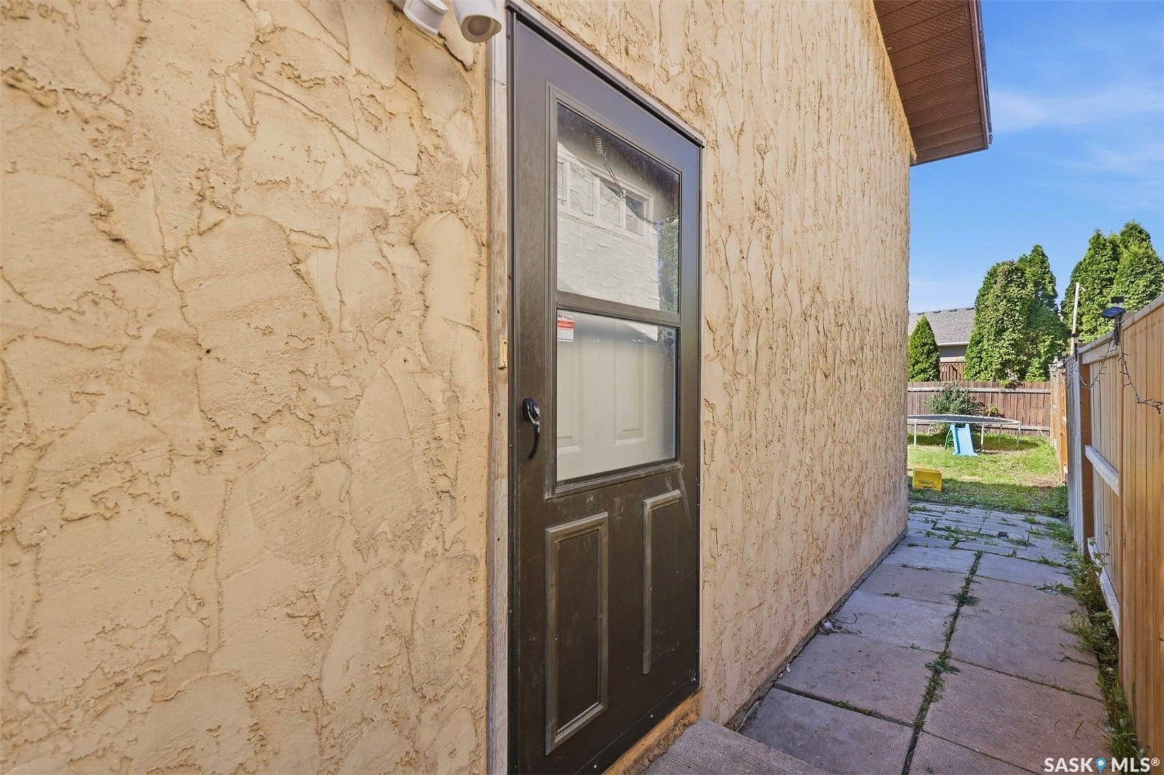 Stucco exterior with a storm door entry