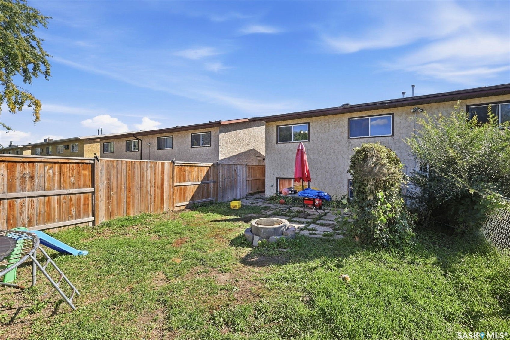 Private backyard with wood fencing, stone patio area, and integrated fire pit