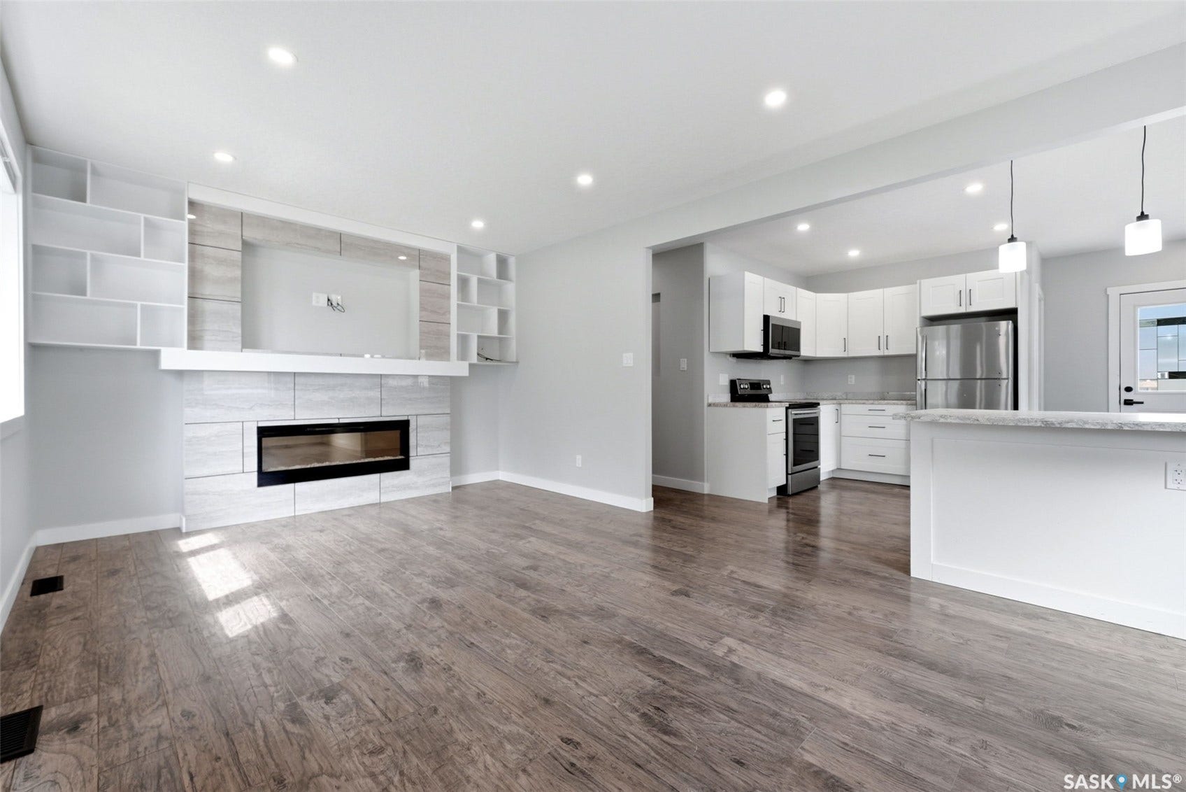 1601 Lacon Street, Regina SK S4N 1Z5 Wood-finish flooring throughout, recessed lighting, and a modern fireplace with a tiled surround and built-in shelving