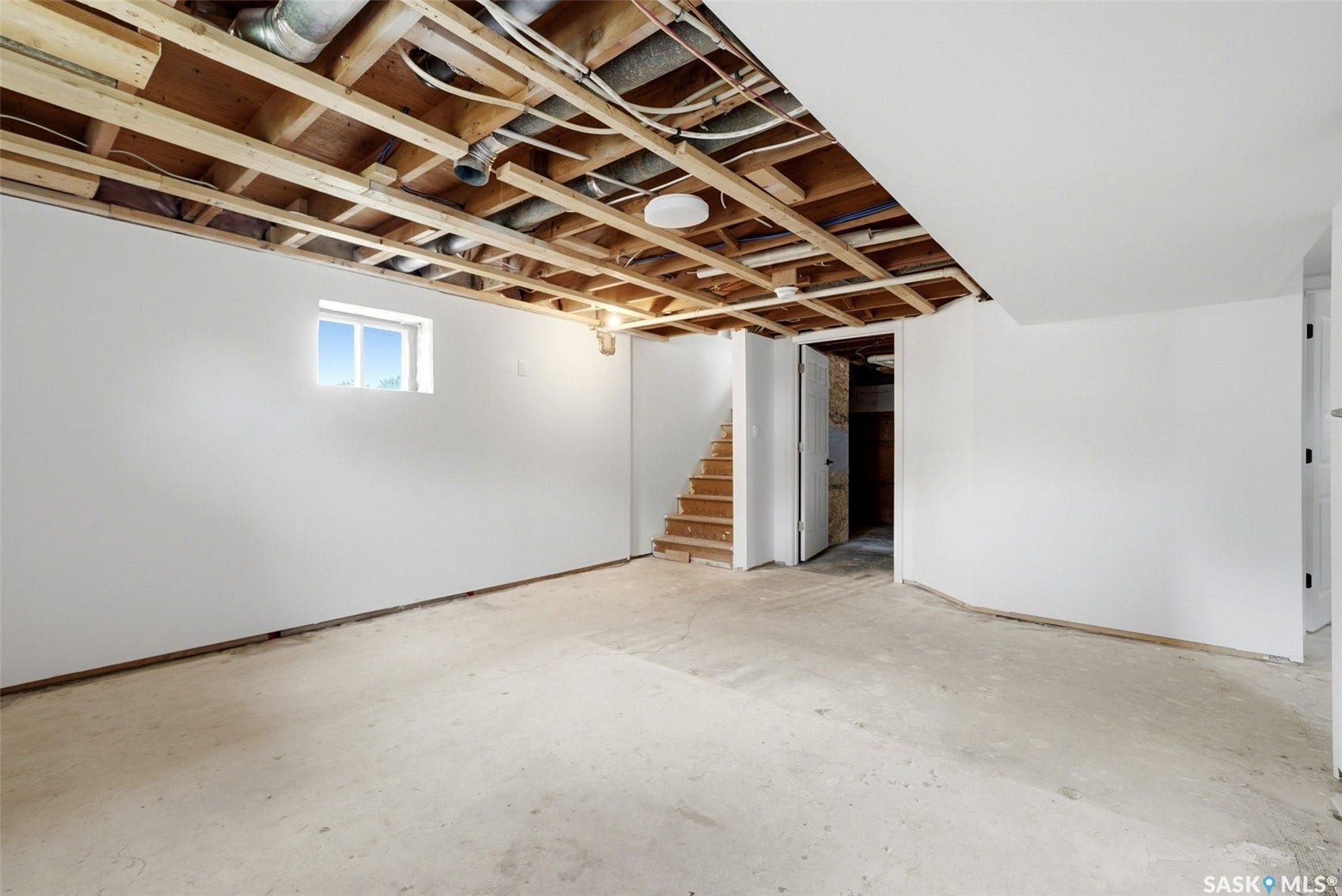 1601 Lacon Street, Regina SK S4N 1Z5 Unfinished basement with exposed ceiling joists, concrete flooring, egress window, and partial finished drywall