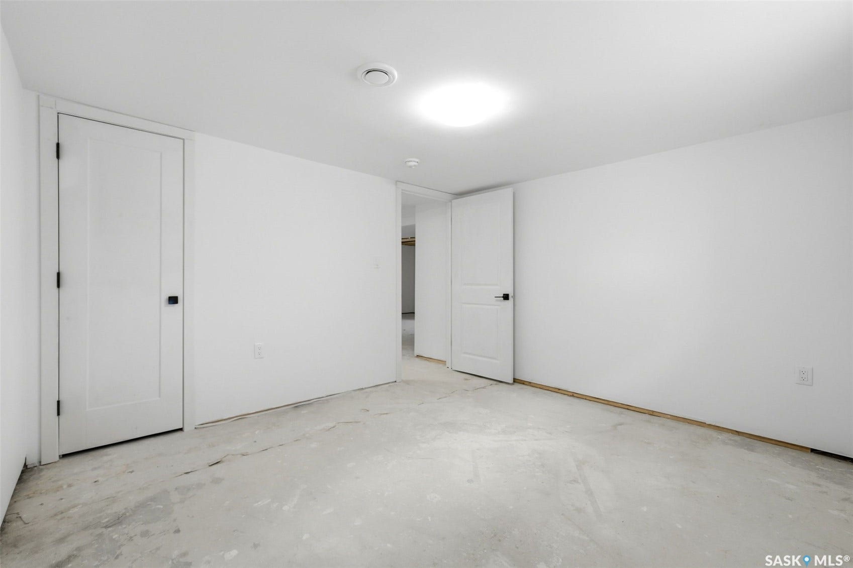 1601 Lacon Street, Regina SK S4N 1Z5 Unfinished concrete flooring, white walls, two interior doors, and overhead lighting